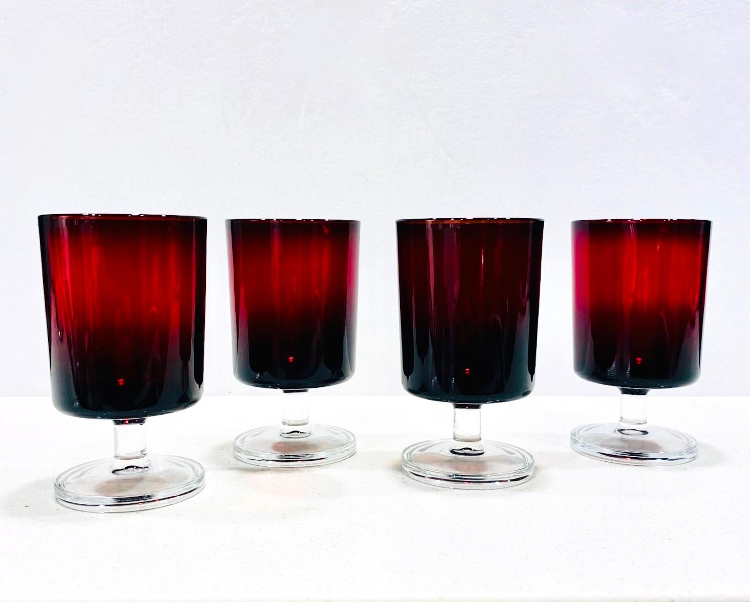 Set of four French Mid-Century Modern Arcoroc wine glasses in a gorgeous deep garnet red with clear glass stems. Glasses have Minimalist design with cylinder forms. Stamped 