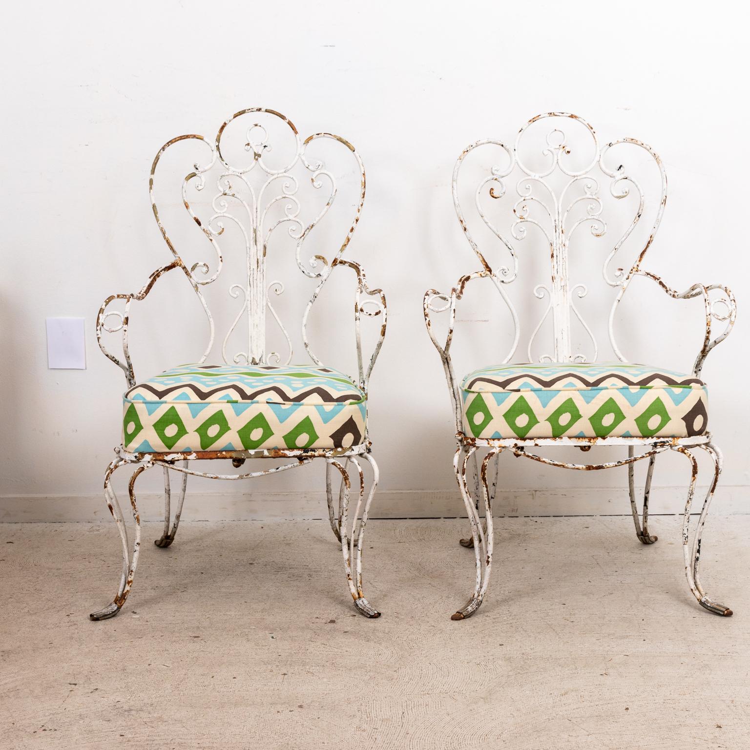 Ensemble de quatre fauteuils en fer forgé peint des années 1940 avec coussins rembourrés dans un tissu quadrille China Seas. Le cadre en fer en forme de s-scroll présente une patine oxydée et rouillée qui peut être facilement repeinte. Les chaises
