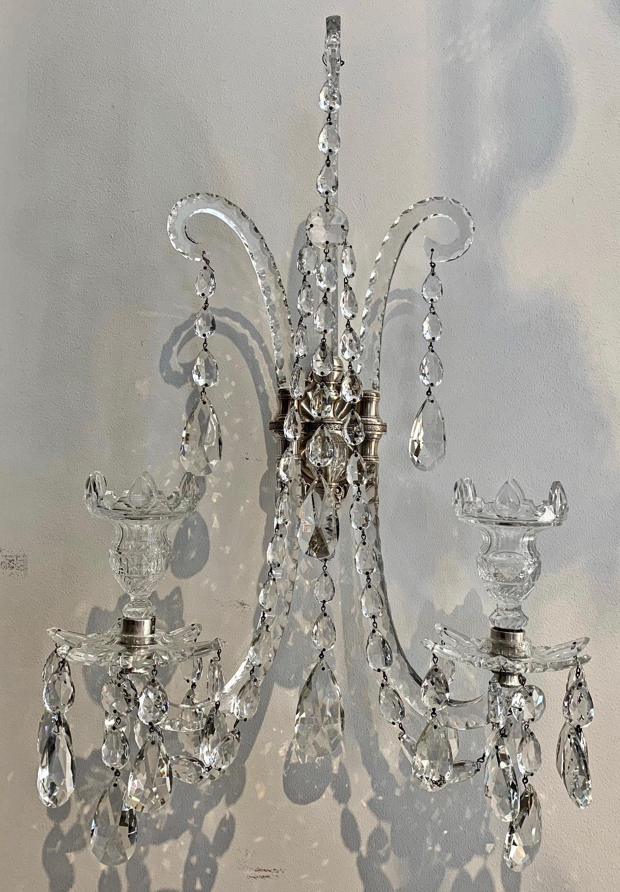 Set of four cut crystal Georgian style wall sconces. Beautifully hand blown and cut crystal two-arm wall sconces. Neoclassical Adam design in late Georgian style. Neoclassical silvered brass backplate. Excellent condition. Crystal all