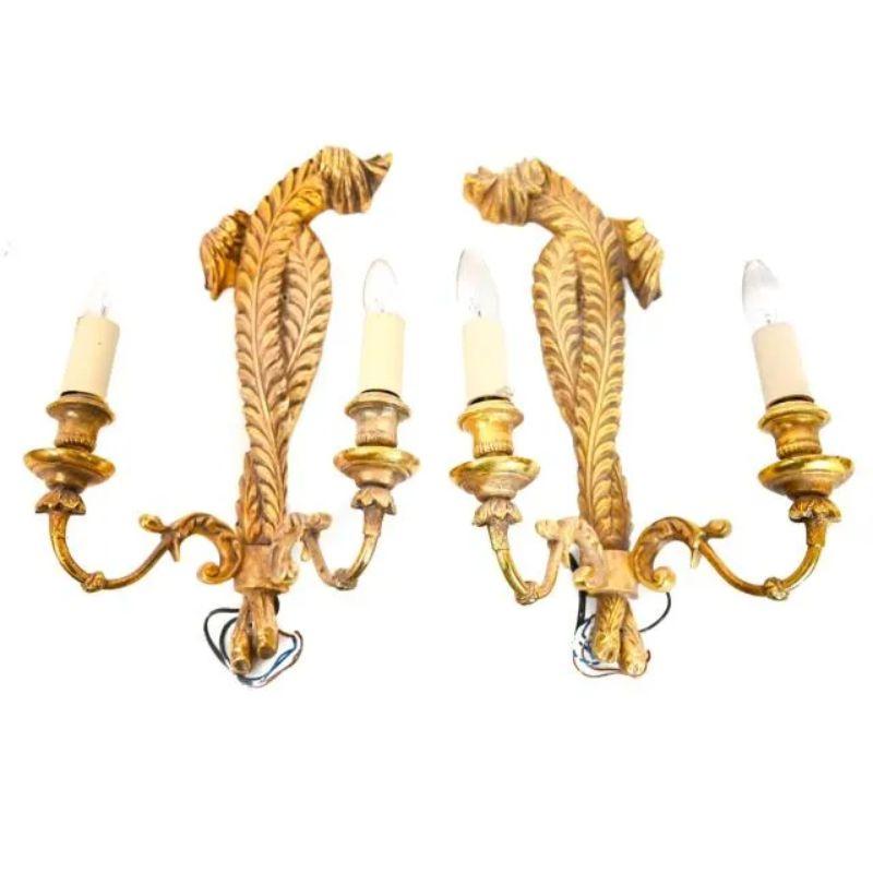 A set of four vintage gilt Prince of Wales plume style wall sconces. Each sconce has two detailed brass curved arms. Two sconces have feather plumes that bend to the right and two sconces have feathers that bend left. A regal addition to a space.