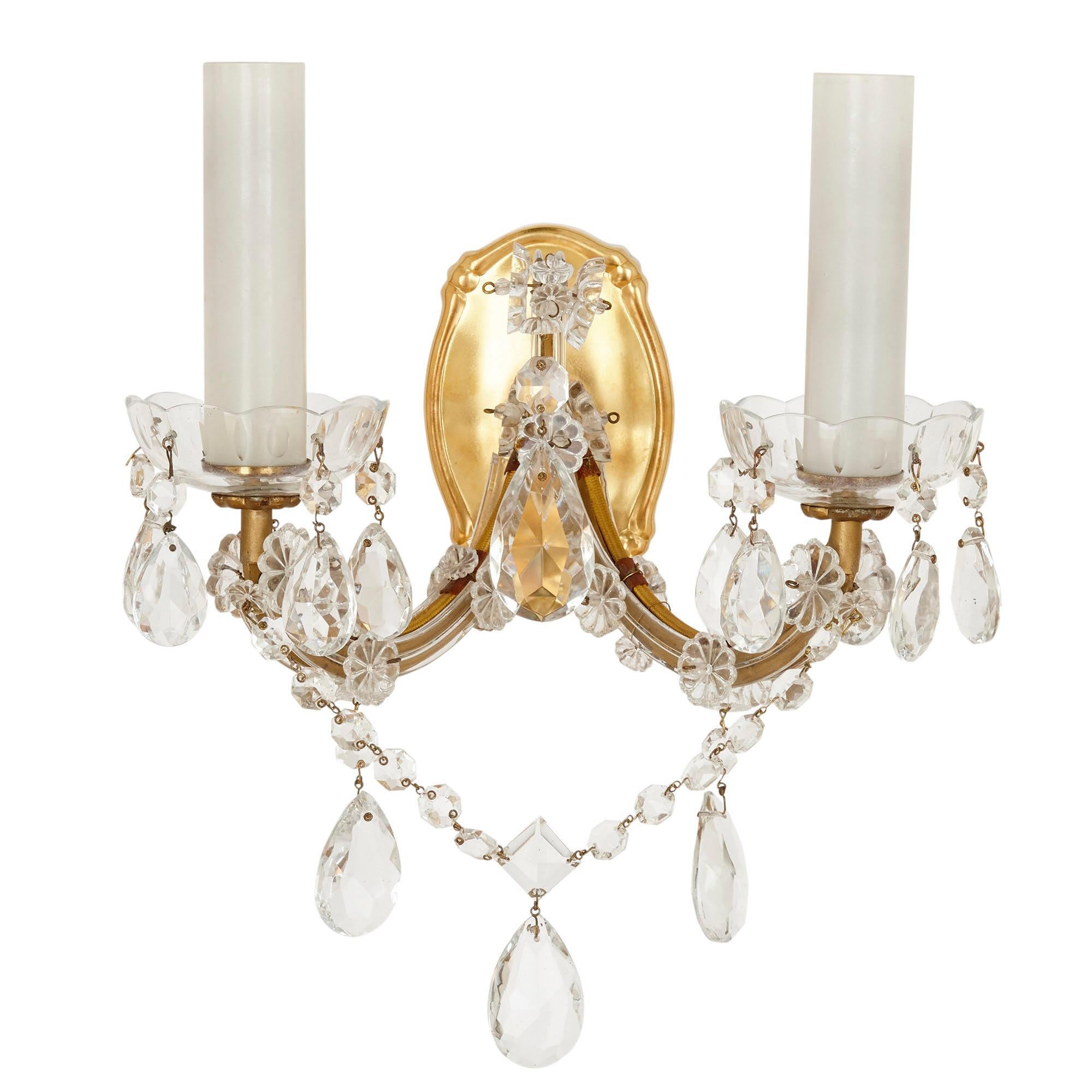 Set of four gilt bronze and Bohemian glass sconces
Bohemian, 20th century
Measures: Height 21cm, width 27cm, depth 19cm

The sconces in this set are crafted from gilt bronze and cut glass. Each sconce features a shaped gilt bronze back plate