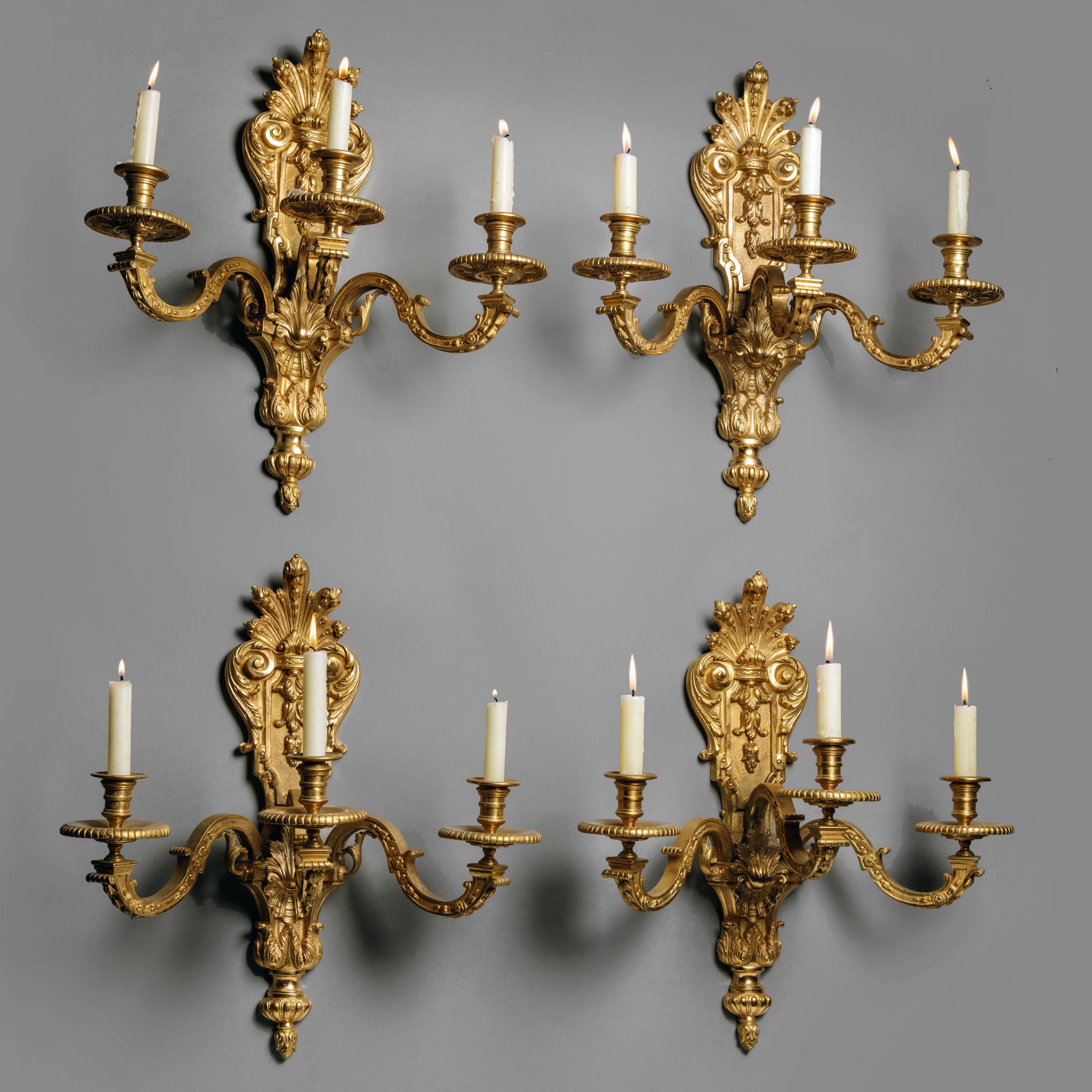 A fine set of four Louis XIV style gilt-bronze wall appliques.

Each applique having a backplate cast with palmettes and fronded acanthus and issuing three scrolling candle arms terminating in gadrooned drip trays and baluster turned
