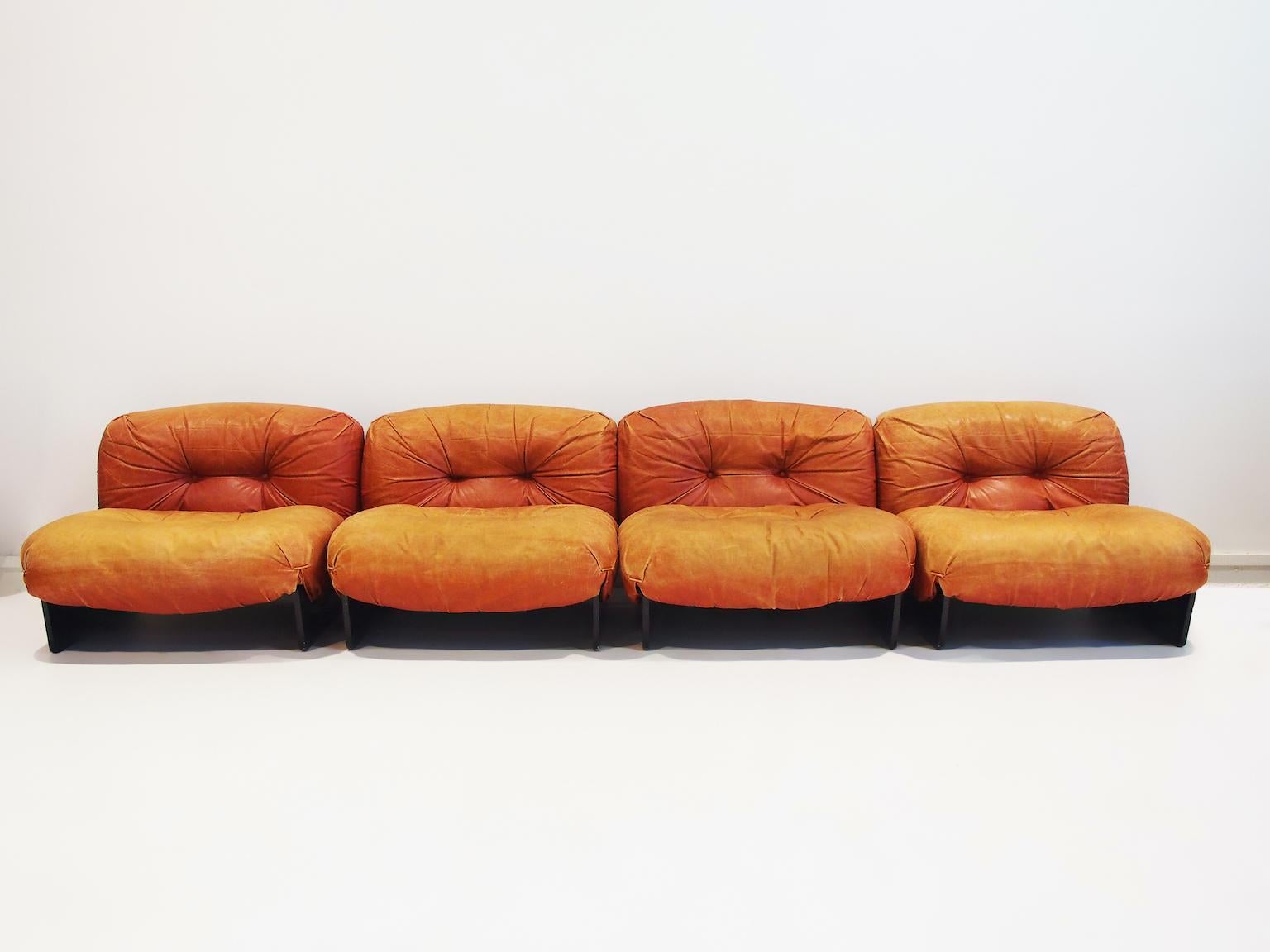 Four modular armchairs that can be combined to a sectional sofa by Giuseppe Munari. Made by Poltrona Munari, circa 1970. Structure in black curved plywood and padding covered in red/cognac color leather. 
