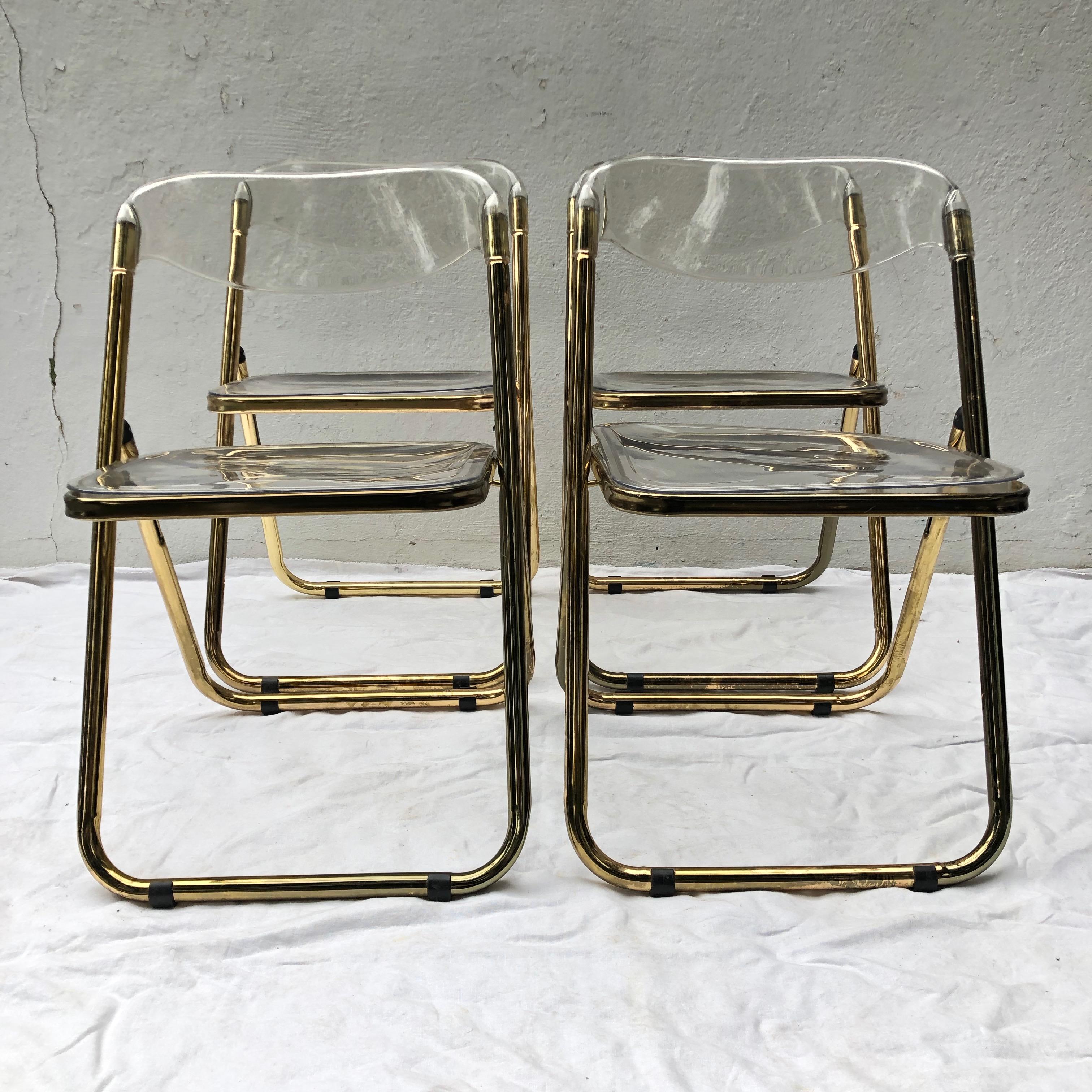 Set of brass Plia folding Lucite chairs in the style of Giancarlo Piretti.