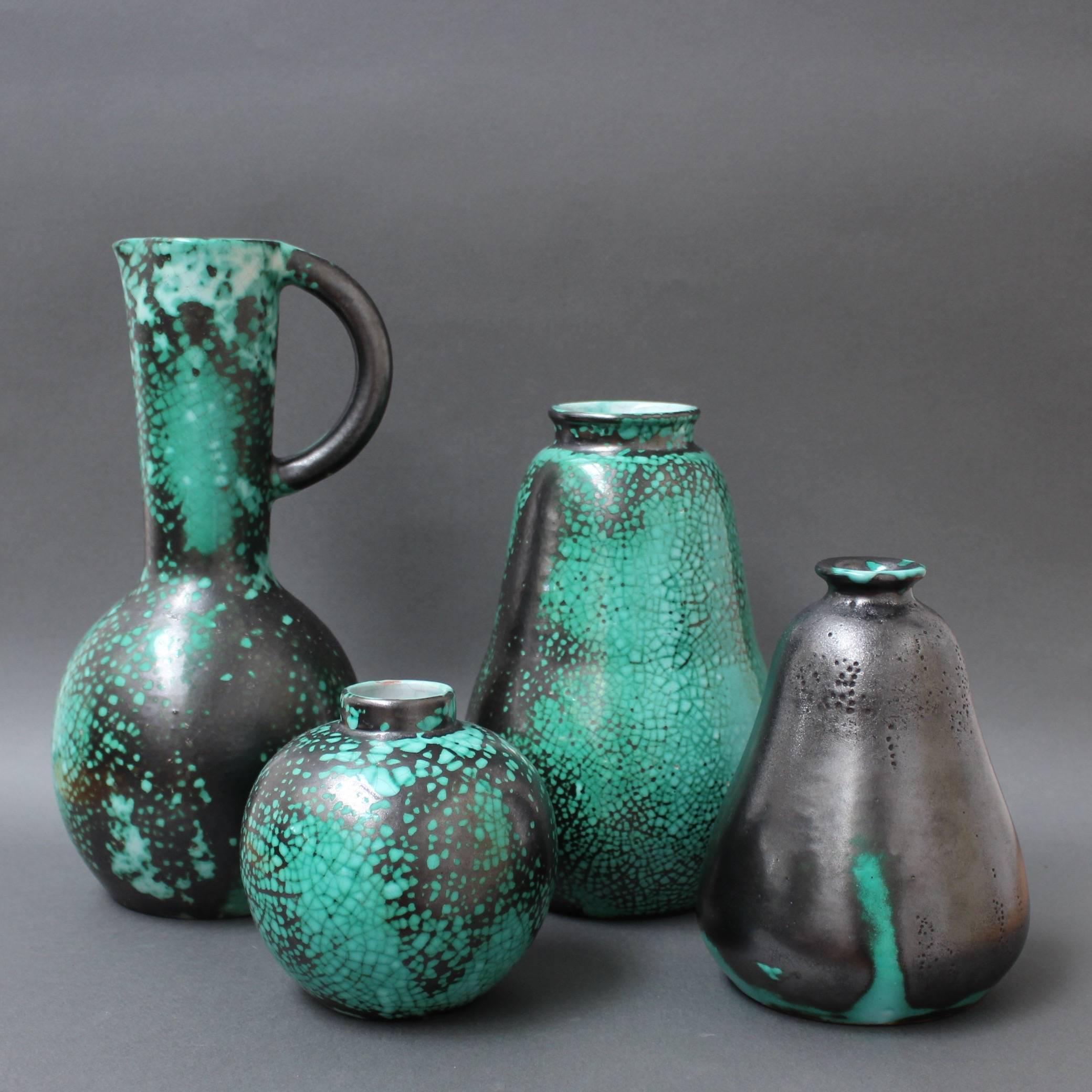 Set of four black and green crackle-glazed ceramic Primavera vases by C.A.B. (Céramique d’art de Bordeaux) for Printemps, circa 1930s. These sensuously curved vases with green coloured bases are covered by a cracked-effect metallic black enamel. The