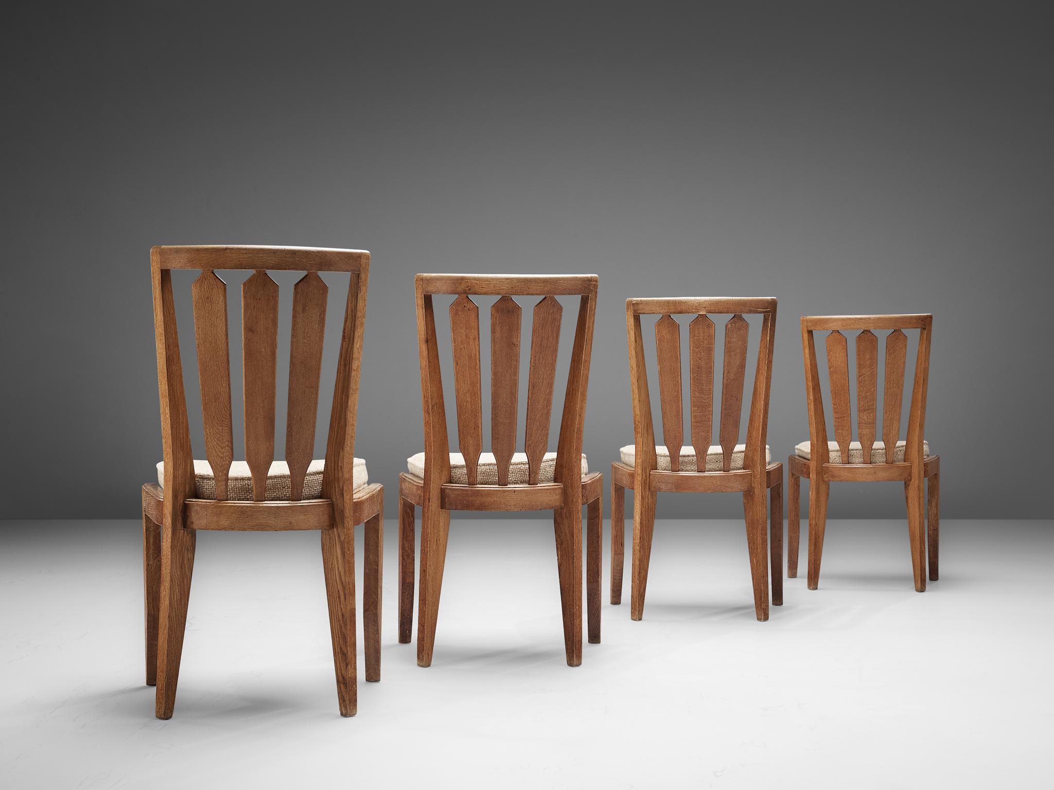 Set of four dining chairs, in oak and fabric upholstery, by Guillerme & Chambron, France, 1960s.

Set of four sturdy, decorative dining chairs in solid oak by Guillerme & Chambron. Notable is the solid oak frame with the highly decorative and