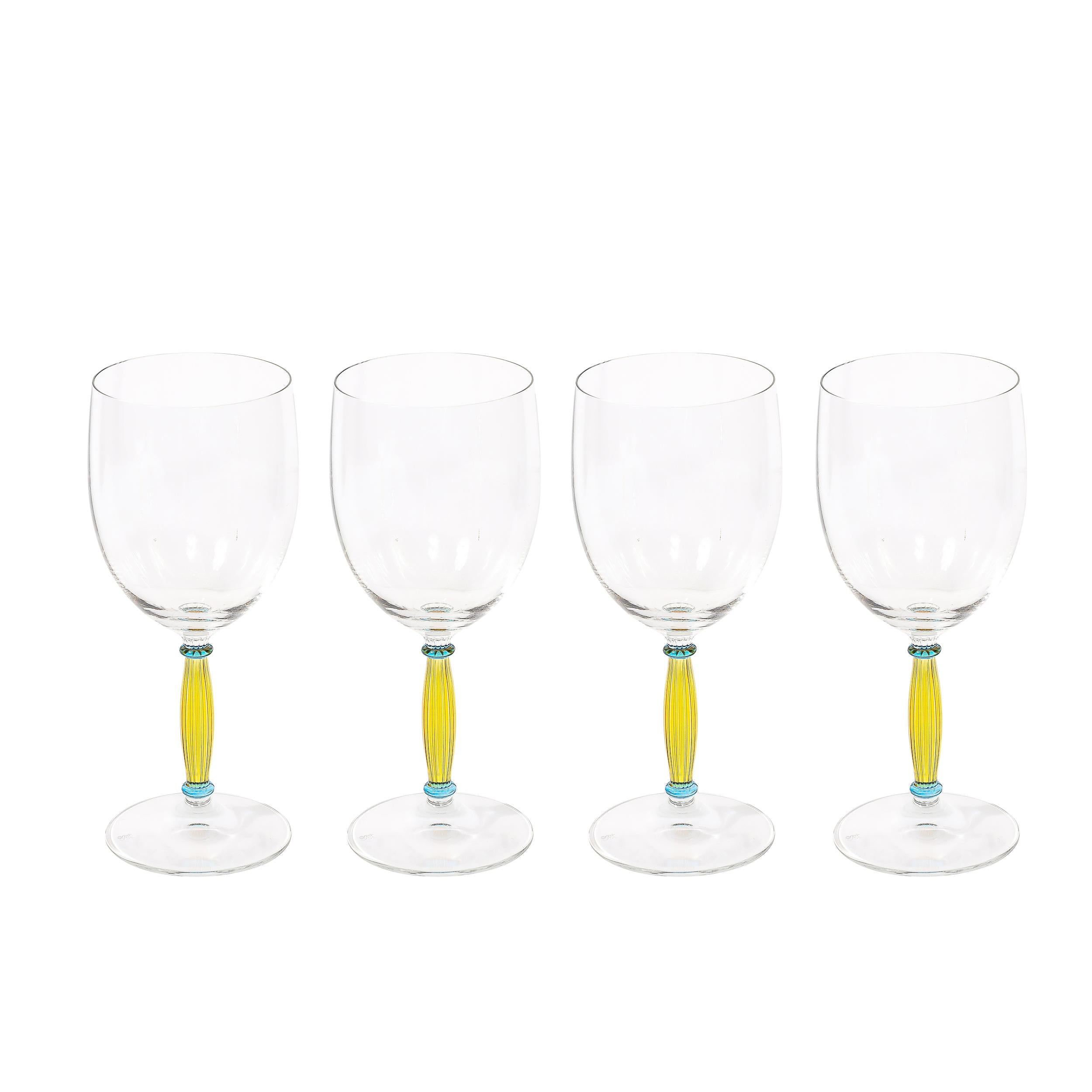 This exquisitely formed Set of Four Hand-Blown Murano Wine Glasses with Citrine & Blue Fluted Stems originates from Italy during the latter half of the 20th Century. Each glass features a classic support and basin, with a beautifully achieved stem