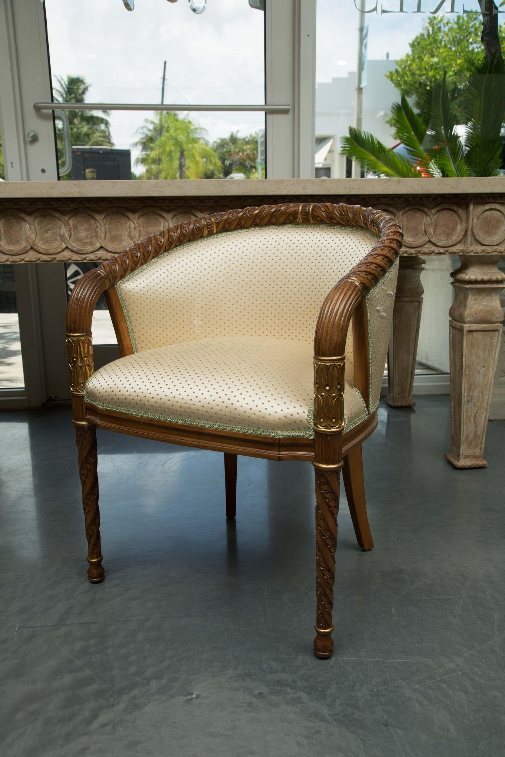 This is a set of four stylish parcel-gilt and mahogany hand carved occasional chairs with barrel back and conforming rope-carved top rail, extending to become arms. The fully upholstered chairs are supported by round tapered graceful rope-carved