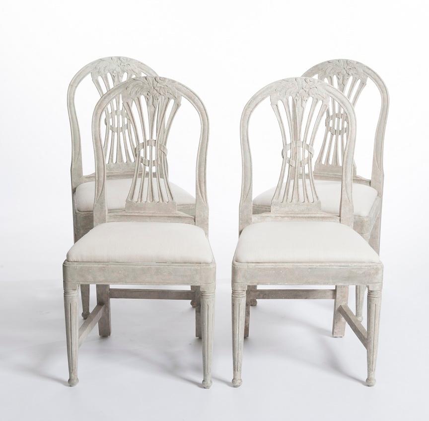 Set of 4 comfortable Gustavian chairs in a balanced proportion.
Rounded backrest and edges.
A bunch of ears of corn is carved into the backrest.
The color is light gray-green and the fabric cover is 100% linen from Romo.