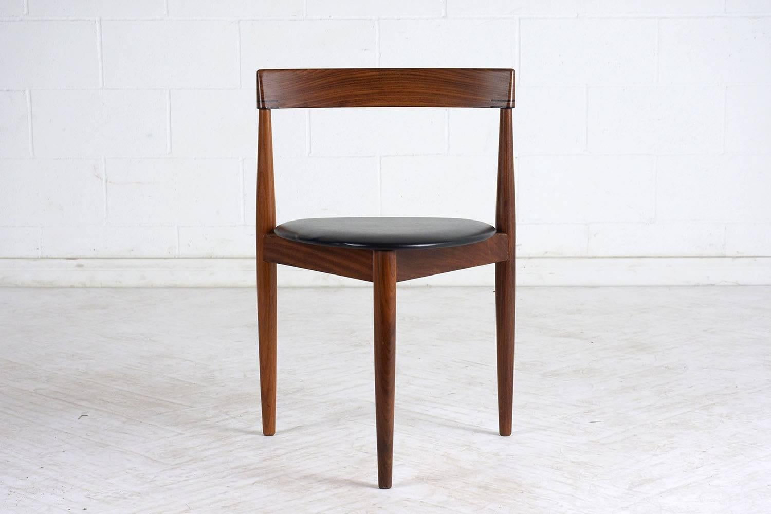 This set of four Hans Olsen dining chairs features beautiful walnut wood frames with the original finish. The triangular seats have been upholstered in black vinyl. Their unique design makes them stand out in any room. The chairs are comfortable,