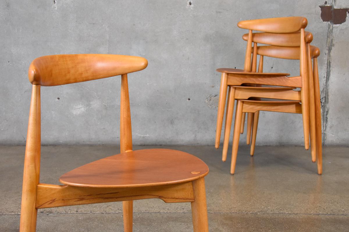 A set of four model FH4103 'heart' chairs designed by Hans Wegner for Fritz Hansen 1952. These examples in beech with teak seats. They have been completely restored and in excellent condition. One retains a faint 'FH' stamp to the