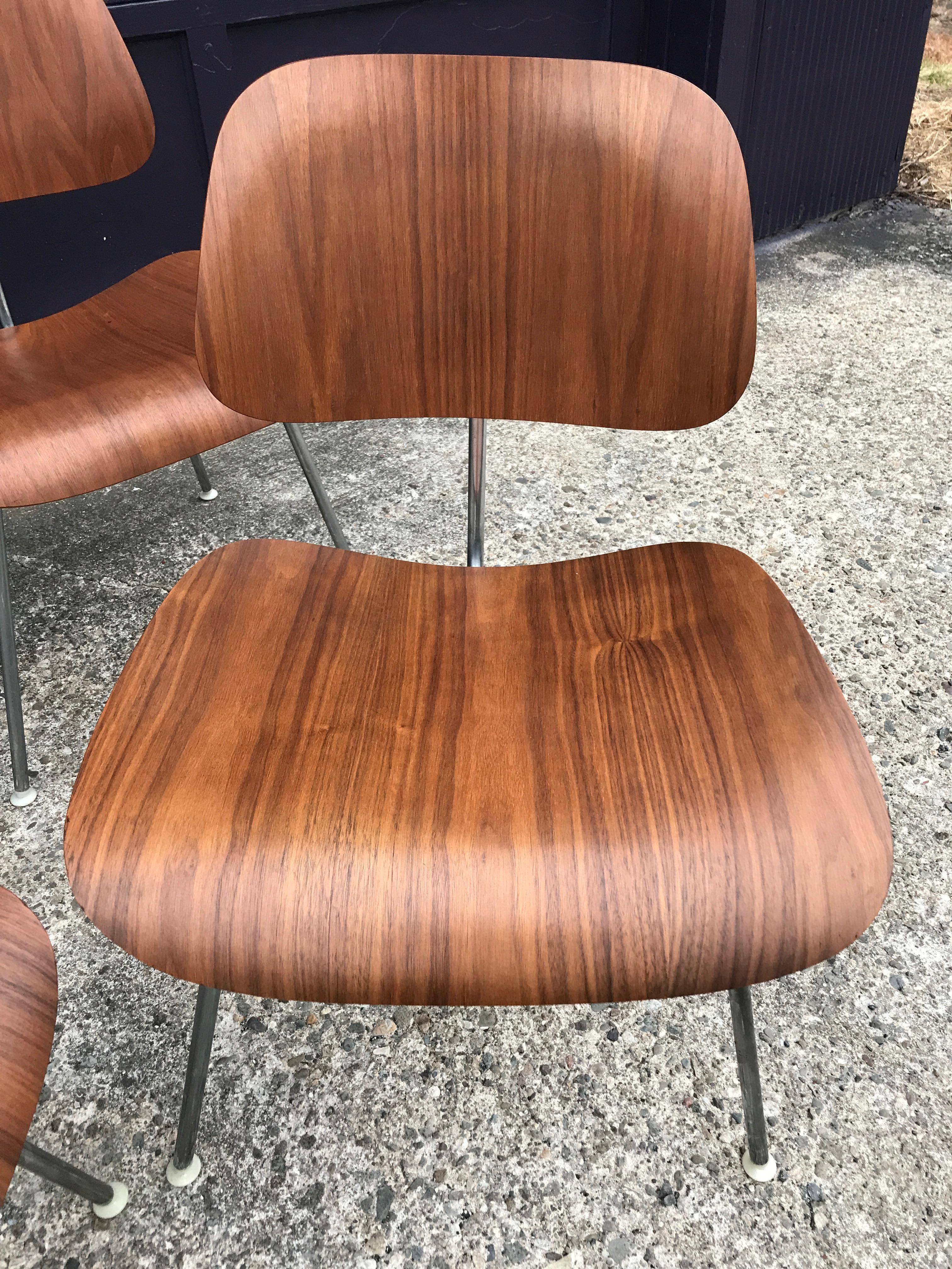 Gorgeous set of 4 matches Herman Miller Eames DCM dining chairs in walnut. Gorgeous vibrant color and amazing grain patterns. Signed with black Herman Miller tags. All nylons glides present for use on different types of floors.