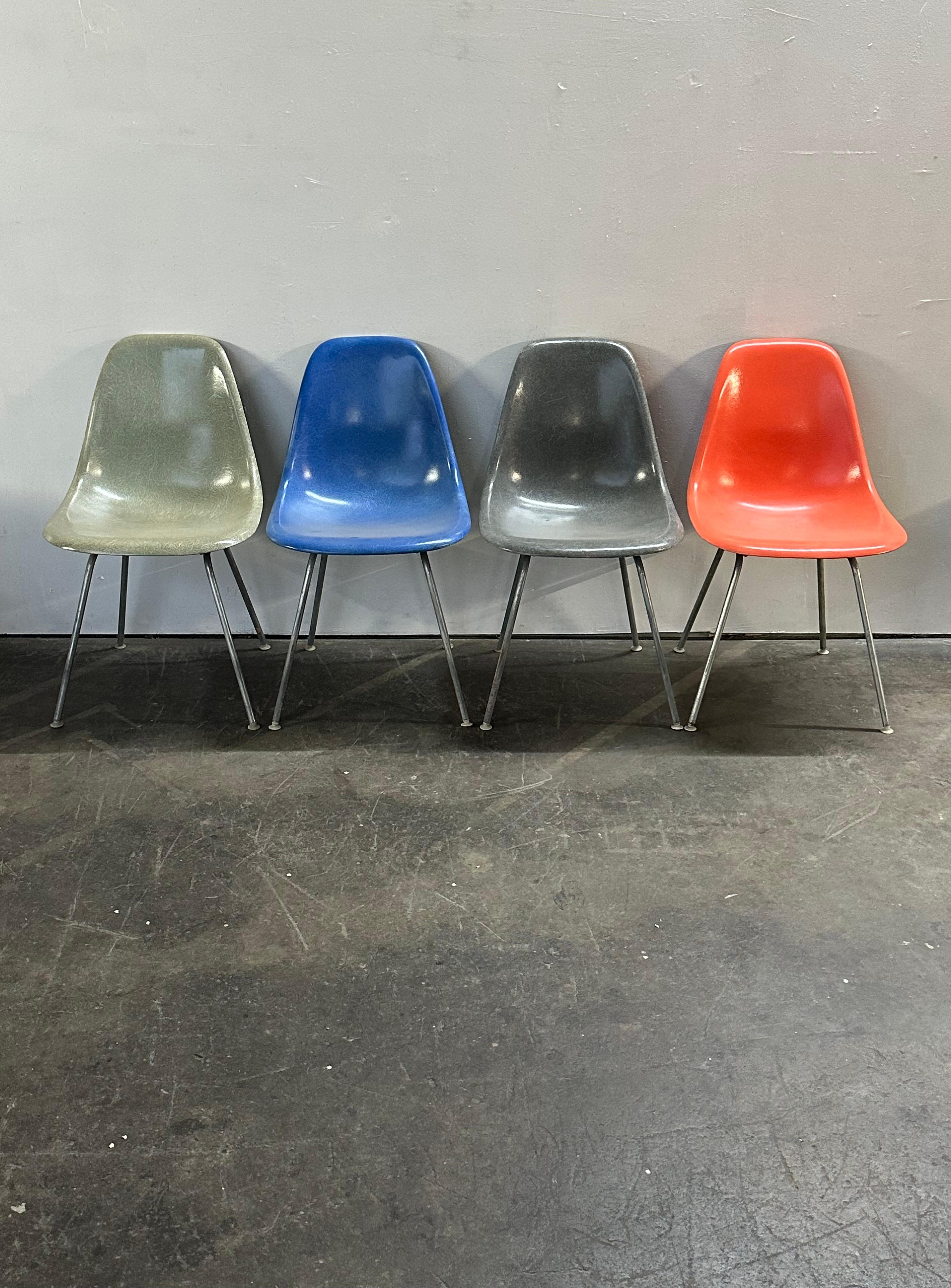 Set di quattro sedie da pranzo vintage in fibra di vetro Herman Miller Eames. Set multicolore con verde acqua, grigio pelle di elefante, rosso arancio e blu reale. Non ci sono crepe o buchi. Tutte le conchiglie sono firmate e garantite come