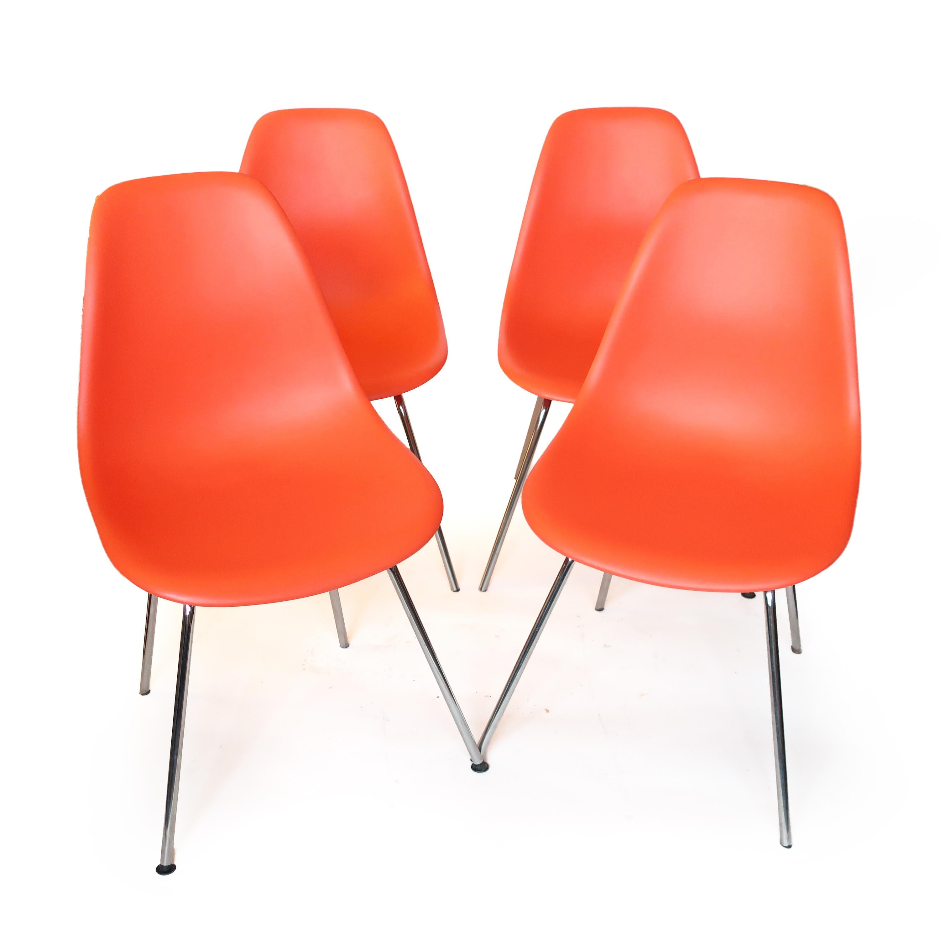 A classic set of four plastic dining chairs designed by Ray and Charles Eames for Herman Miller. Shells are red orange and the bases are chrome. All chairs are from same owner so they have aged together and are an original set. 

In very good