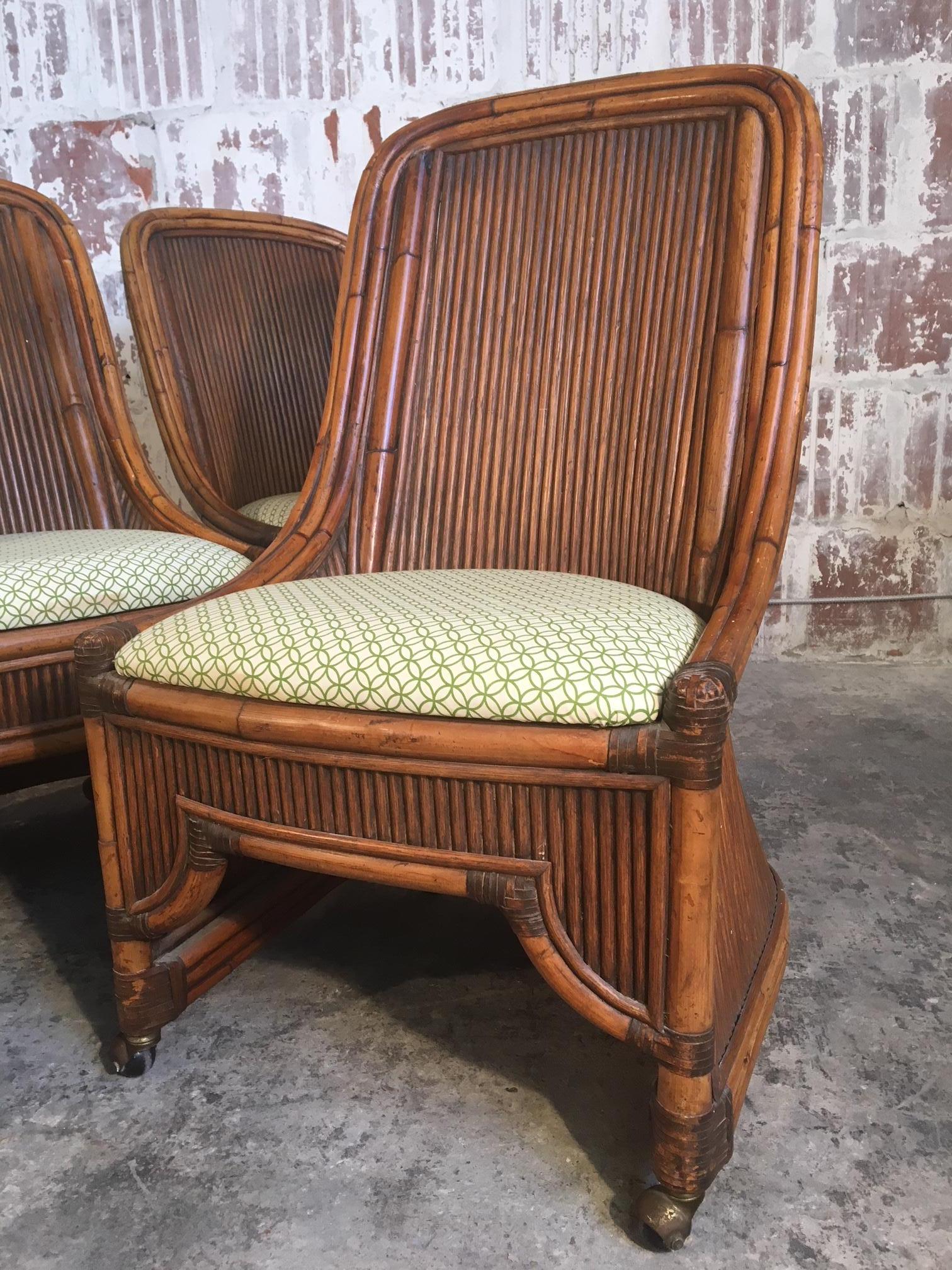 Set of 4 rattan dining chairs feature high back bamboo framework and caster wheels. Very good vintage condition with very minor signs of age appropriate wear. Upholstery free of stains or wear.  Professional reupholstery available, ask for details.