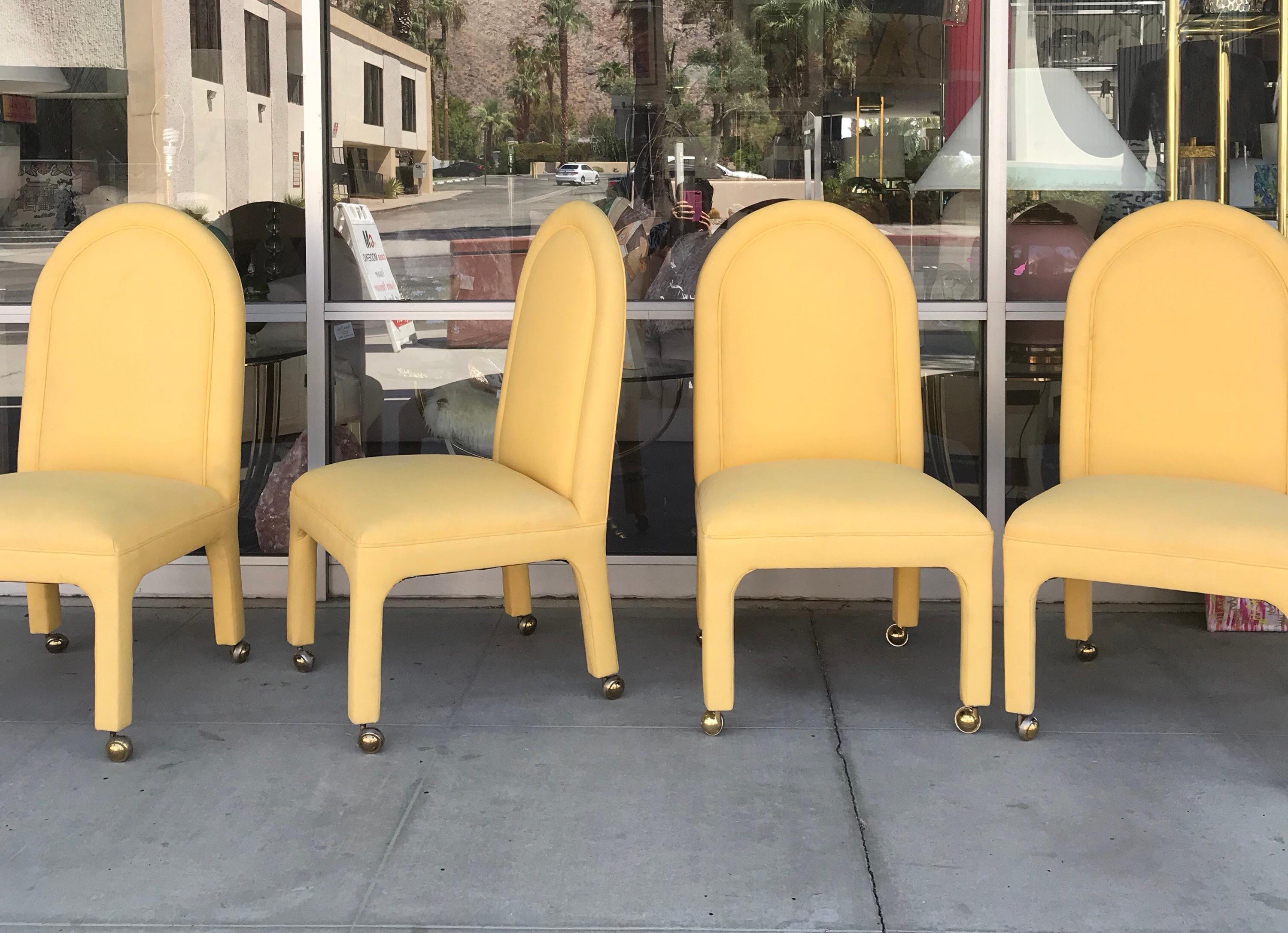 A set of four patio dining chairs perfect for indoor or outdoor use done in real Sunbrella fabric. Modern, classic Hollywood Regency styling. Original brass casters for easy mobility. From a very cool vintage Palm Springs Estate.
