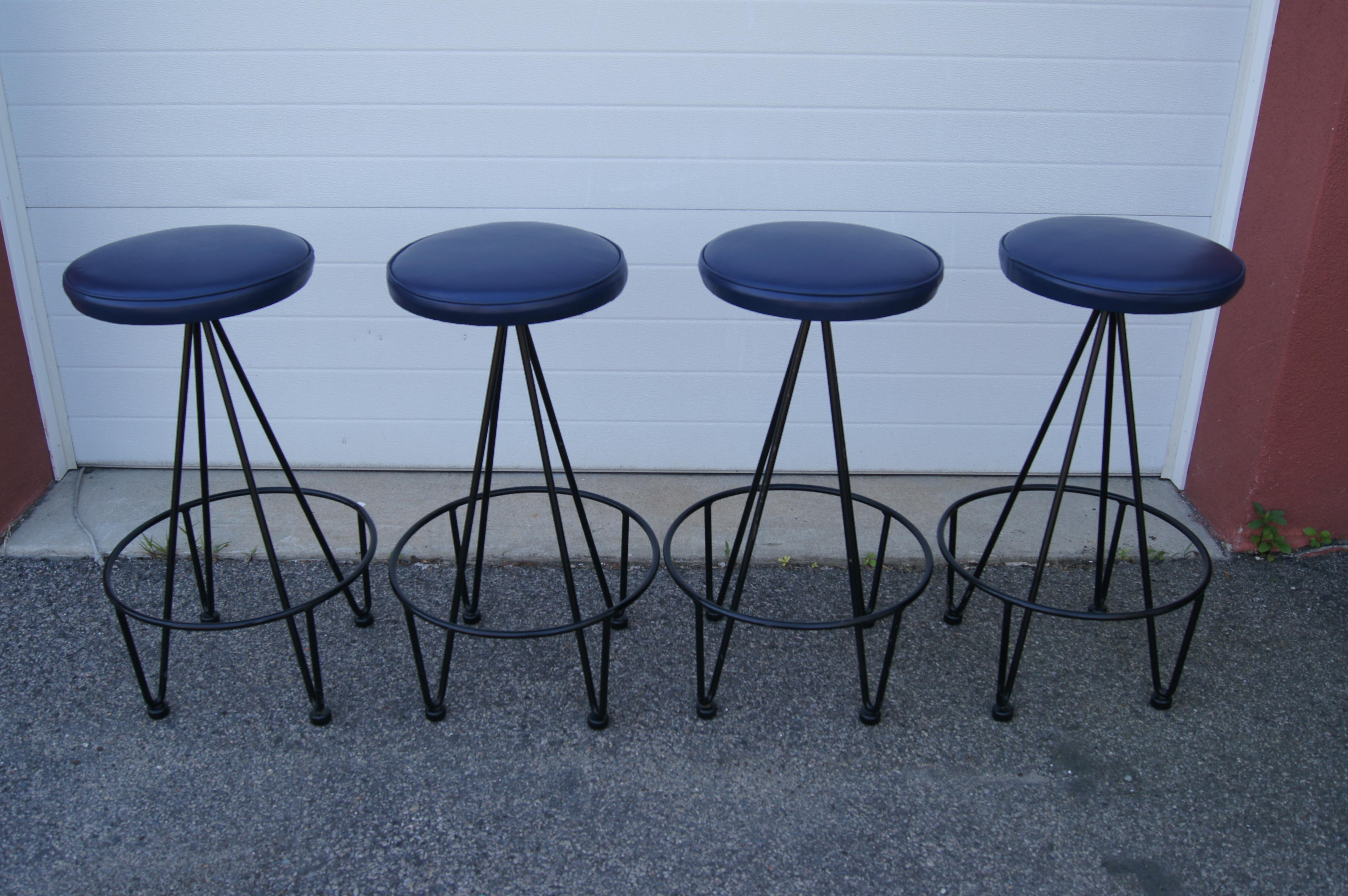 Philadelphia-based artist and industrial designer Frederic Weinberg created these classic mid-century modern bar stools. This set of four features wrought-iron frames with hairpin legs and comfortable round seats, here in deep blue leather.