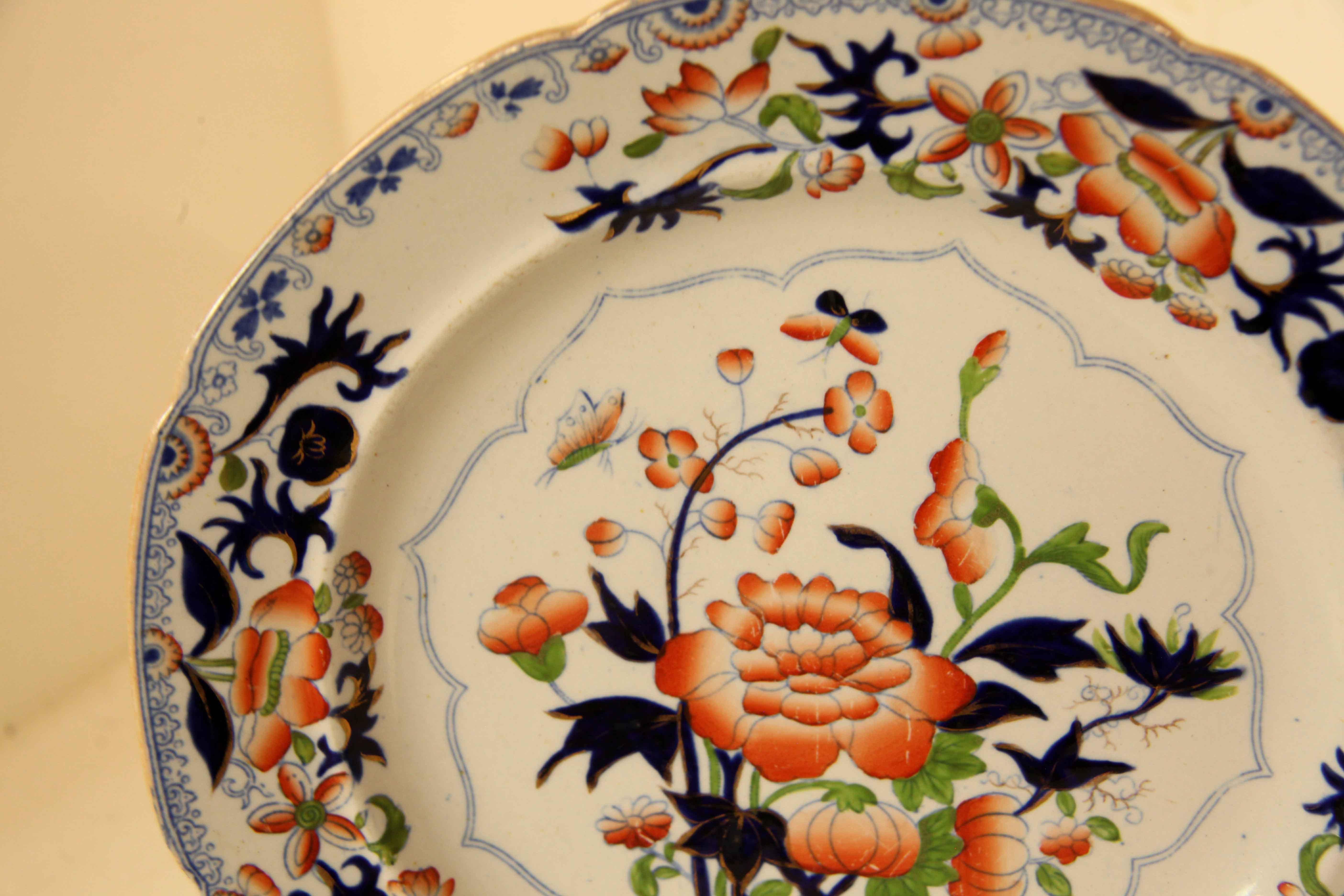 Satz mit vier Tellern aus Eisenstein,  Diese reich verzierten Teller zeigen große und kleine Blumen und Blätter in verschiedenen Orange- und Blautönen, Grün und Weiß mit vergoldeten Akzenten.  Diese haben das zusätzliche Merkmal der fetten 