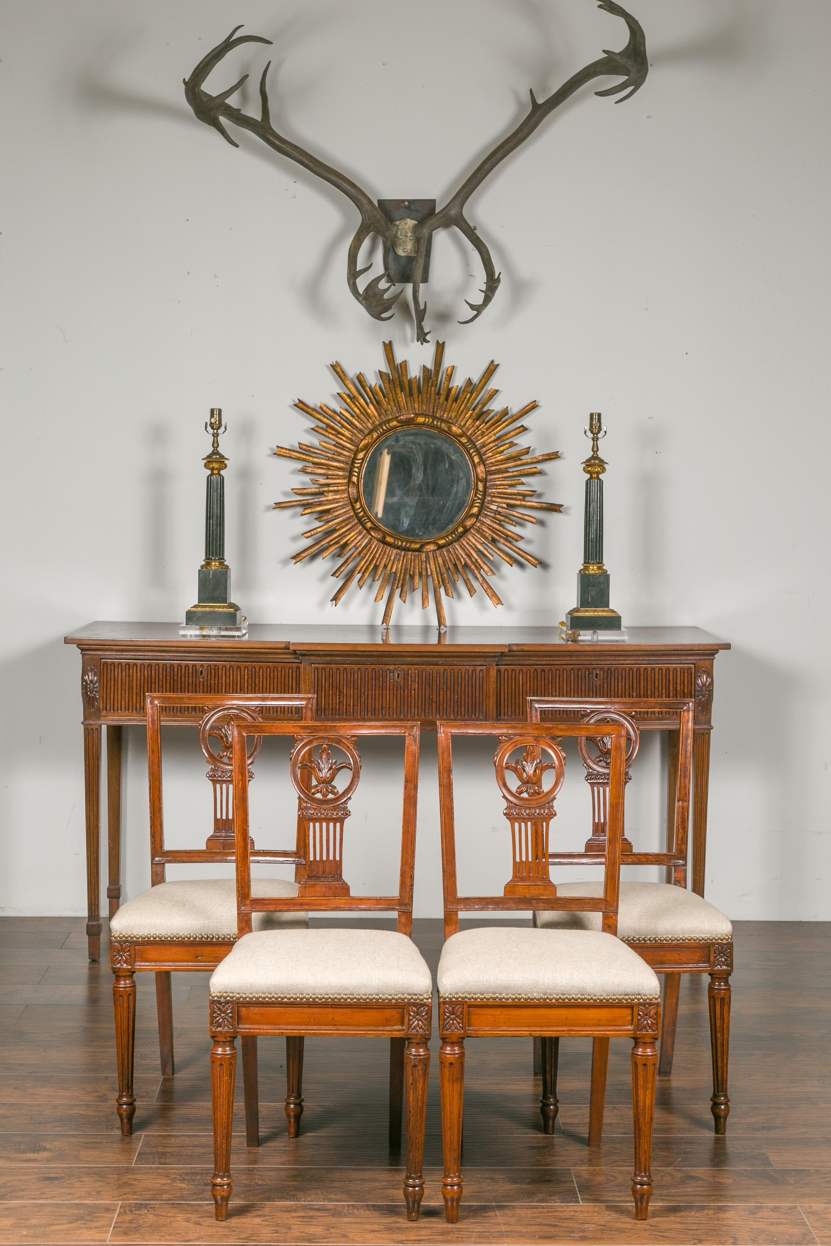 A set of four Italian neoclassical walnut dining room side chairs from the early 19th century, with carved splat, fluted legs and new upholstery. Born in Italy during the first quarter of the 19th century, each of this set of four side chairs