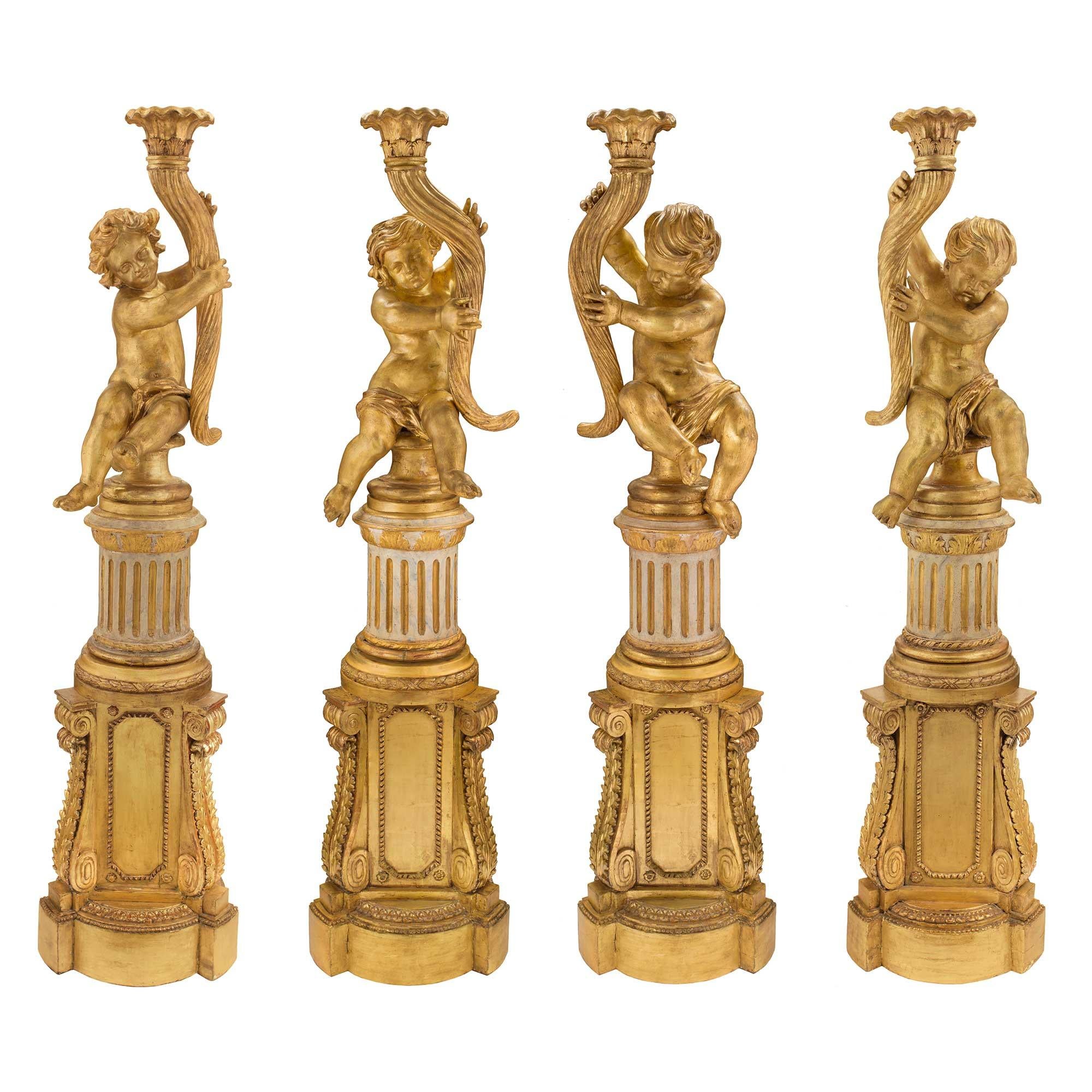A sensational and extremely decorative complete set of four Italian 18th century Louis XVI period patinated off white and giltwood cherub Torchières. Each is raised by impressive gilt pedestals decorated by large richly carved acanthus leaves,