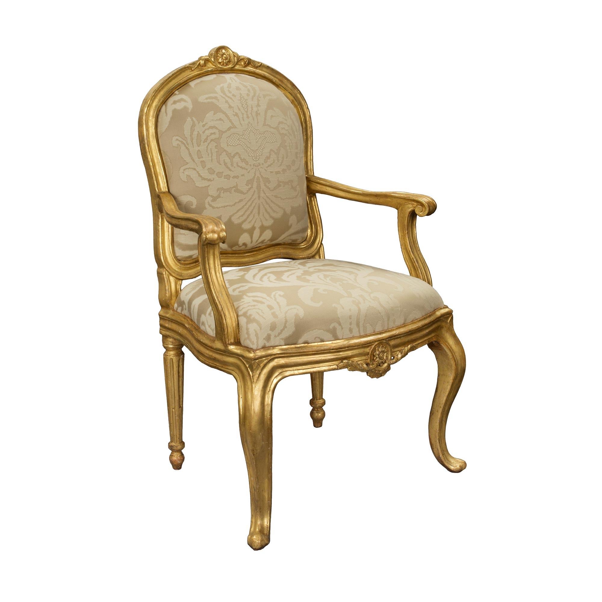 A striking and most unique complete set of four Italian 18th century Transitional Period giltwood armchairs. Each armchair is raised by superb cabriole legs at the front and elegant circular tapered fluted legs to the rear. The frieze displays an