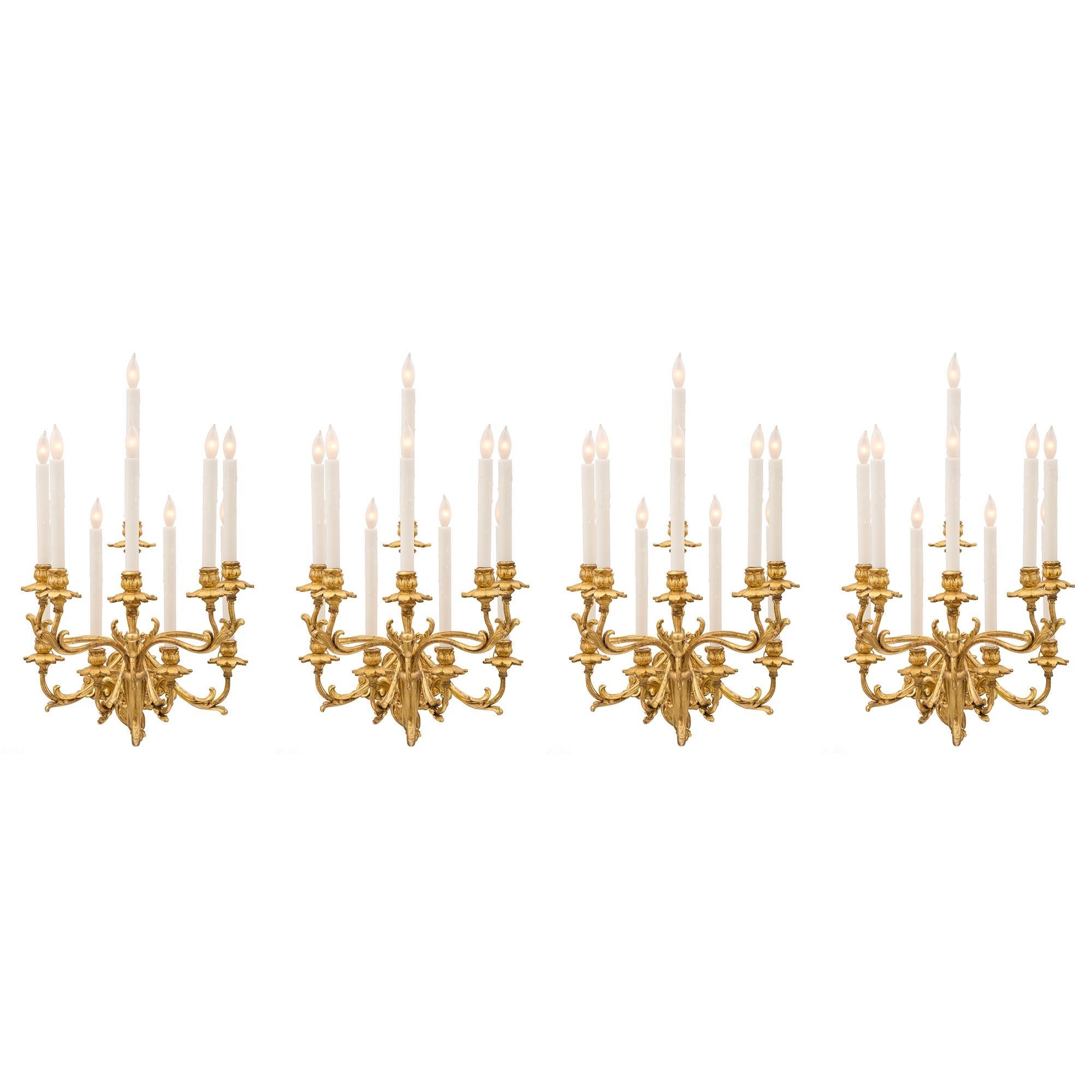 Eine beeindruckende und monumentale Reihe von vier italienischen Rokoko-Leuchten aus vergoldetem Holz und vergoldetem Metall aus dem frühen 19. Jede zehnarmige Leuchte wird von einer schönen verschnörkelten, mit Blättern verzierten Rückenplatte