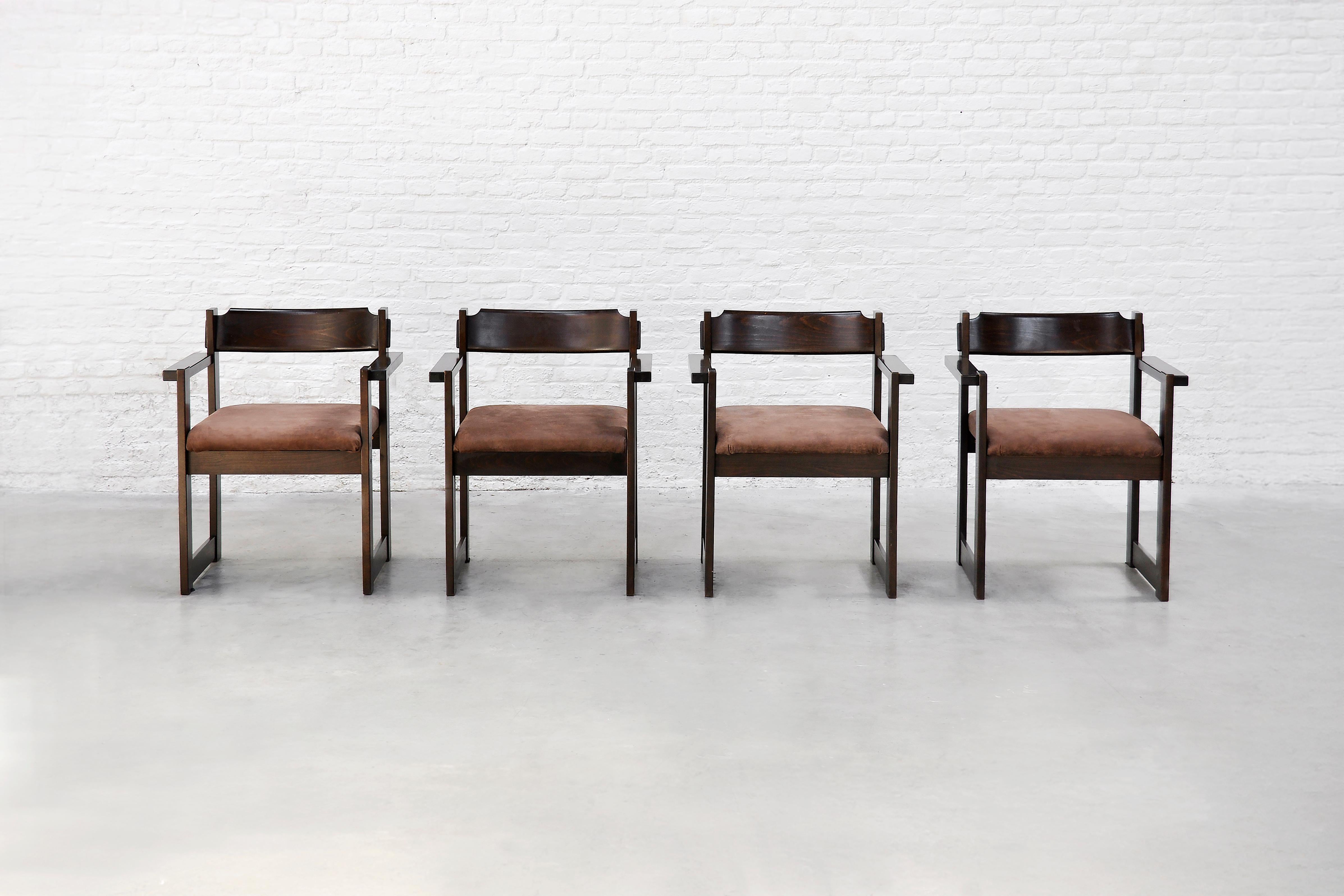 A set of four mid-century dining chairs with a clean architectural presence, produced in Italy in the 1960s. Defined by their structured linear frames and sculptural profiles, these chairs are made from stained hardwood and feature gently curved