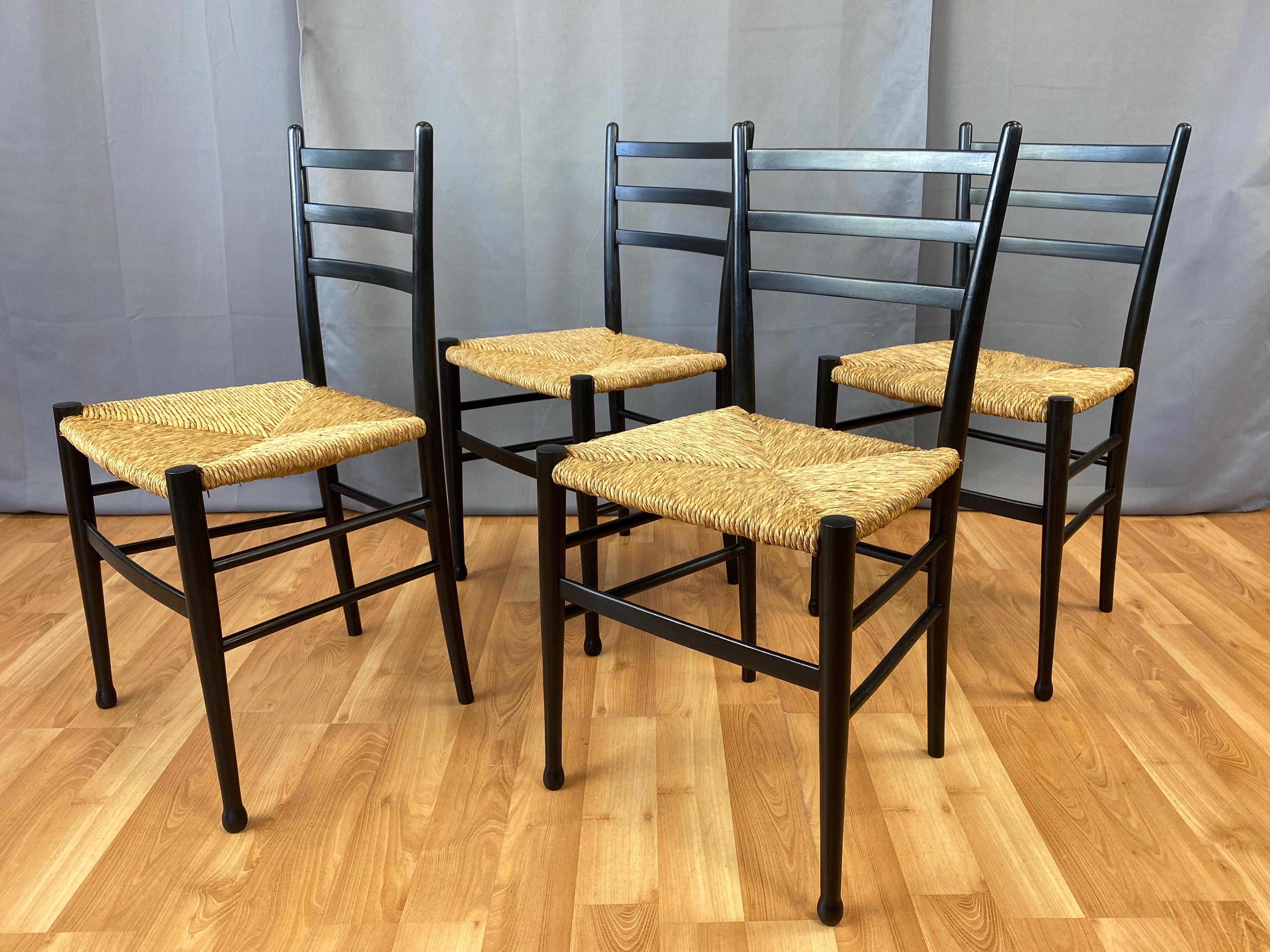 A very handsome set of four late 1960s Italian ebonized wood ladder back side or dining chairs with woven rush seats, similar to iconic designs by Gio Ponti.

Spry frame with slightly splayed three-slat back, and notable for front legs with a