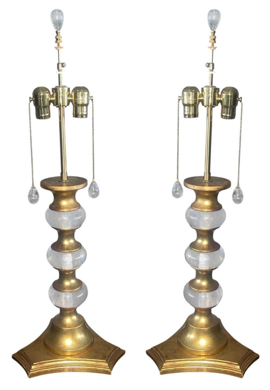 Elegante paire de lampes de table italiennes, chacune taillée et polie à la main dans du cristal de roche et montée sur des bases en bois doré à la feuille d'or 22 carats. Les formes sculpturales présentent une alternance de sections de cristal