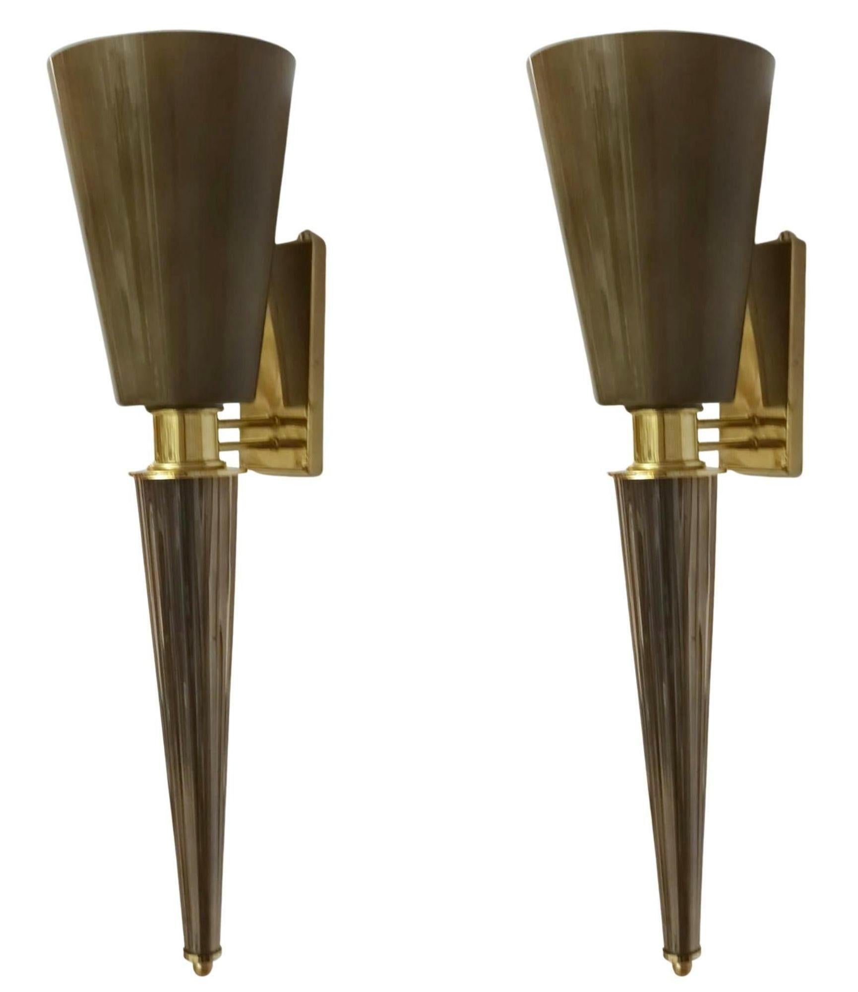 Elegante e scultoreo, questo set di quattro applique torchère italiane degli anni '70 mette in mostra la raffinata arte del vetro di Murano soffiato a mano. Ogni applique è dotata di un elegante paralume grigio fumo a forma di cono, che offre una