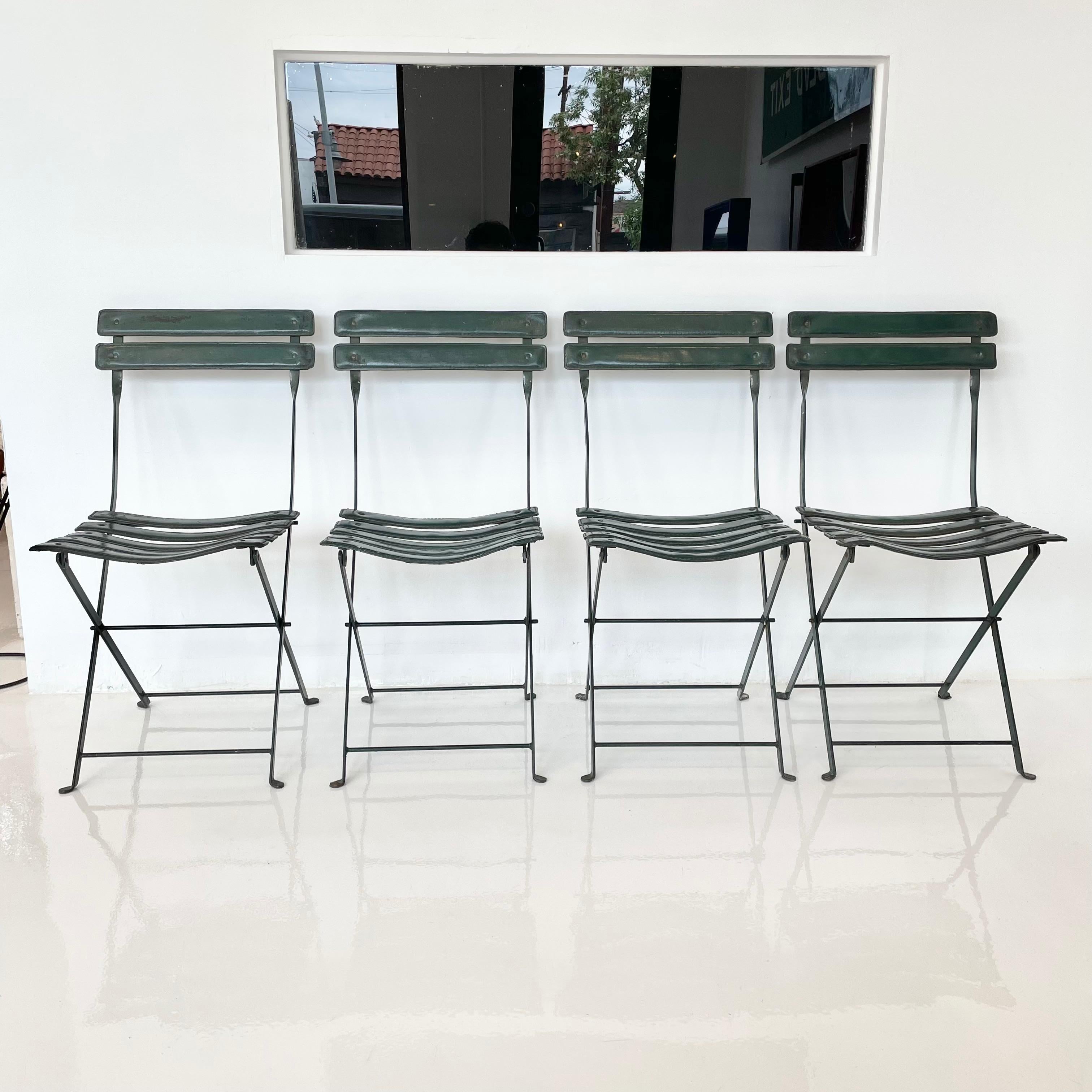 Extremely rare set of 4 dark green folding leather and iron chairs by French designer Jacques Adnet. Slats for seat bottom and seat back all wrapped in leather and supported with a dark green iron frame. Original leather in good condition. Signature