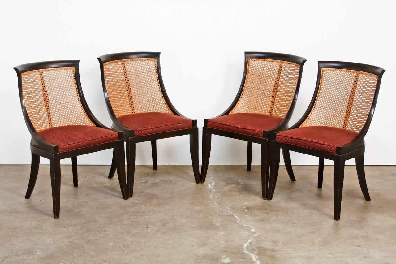 Wicked set of four mid-century ebonized and caned dining chairs made in the manner of James Mont. The chairs have a scoop back or spoon back style design with a scrolled lip on the top. The seats have a geometric Asian pattern upholstery in a