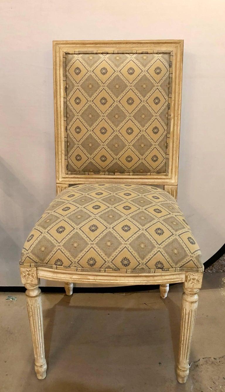 Set of four Maison Jansen Louis XVI style dining chairs in a fine parcel-gilt and paint decorated finish having new upholstery. This wonderful set of custom dining chairs have a Venetian style finish with all over crackle-ware of linen white and a