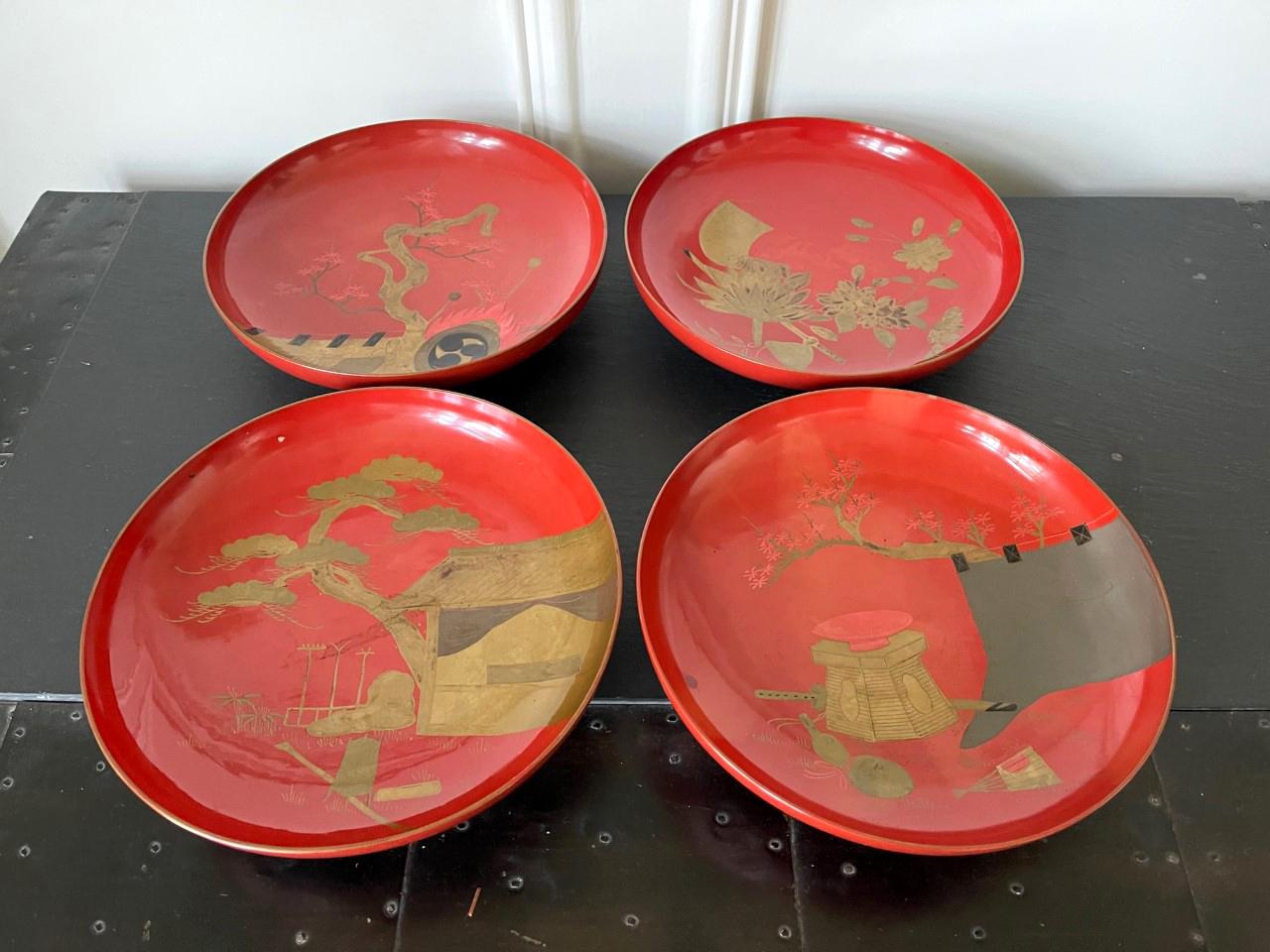 A set of four Japanese shallow footed bowls or dishes in red lacquer with predominantly gold Makie design circa 1920s-1930s Taisho period. Each was decorated with hiramakie painting of different motifs, mostly gold, black and pewter color. One with