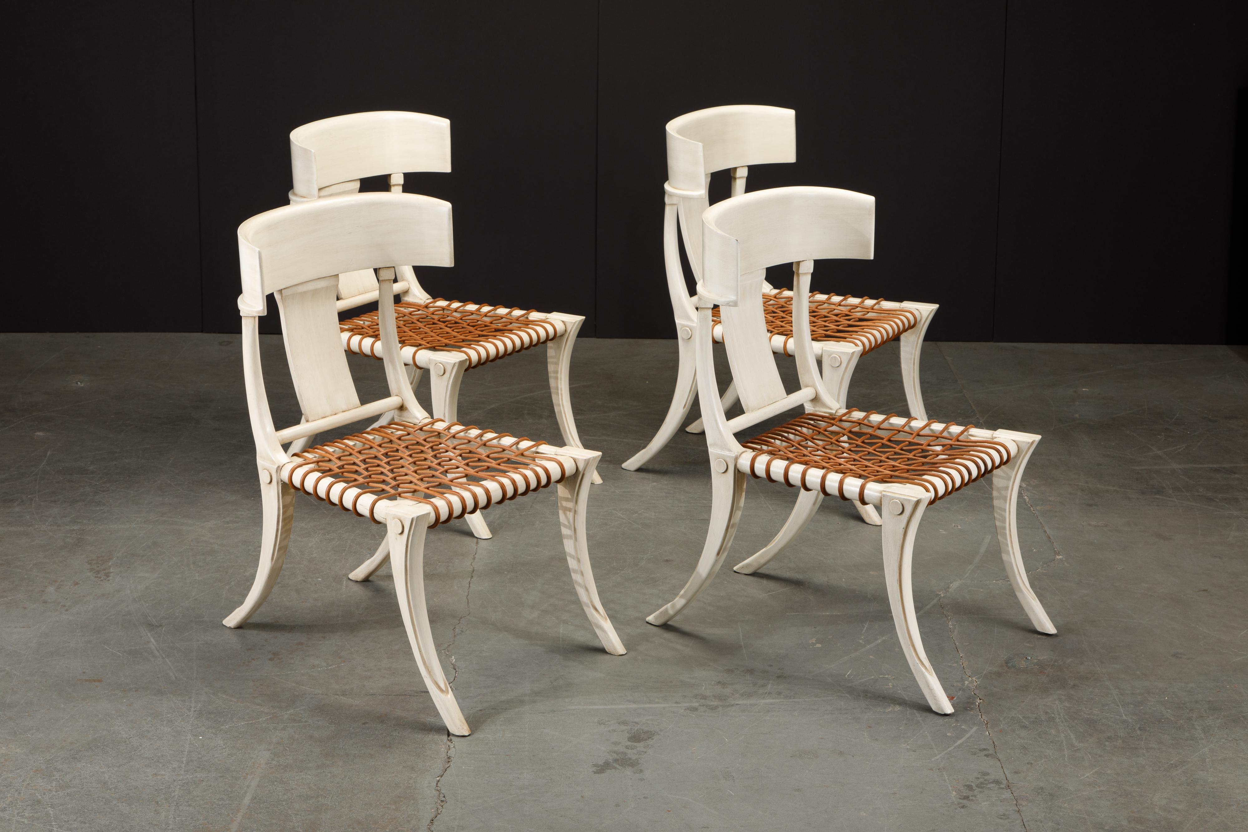 A set of four Klismos chairs in the style of T.H. Robsjohn Gibbings featuring off-white wood frames with leather strap seats. 

These Klismos chairs would work great in a Mid-Century Modern, Scandanavian Modern or Danish Modern home or penthouse