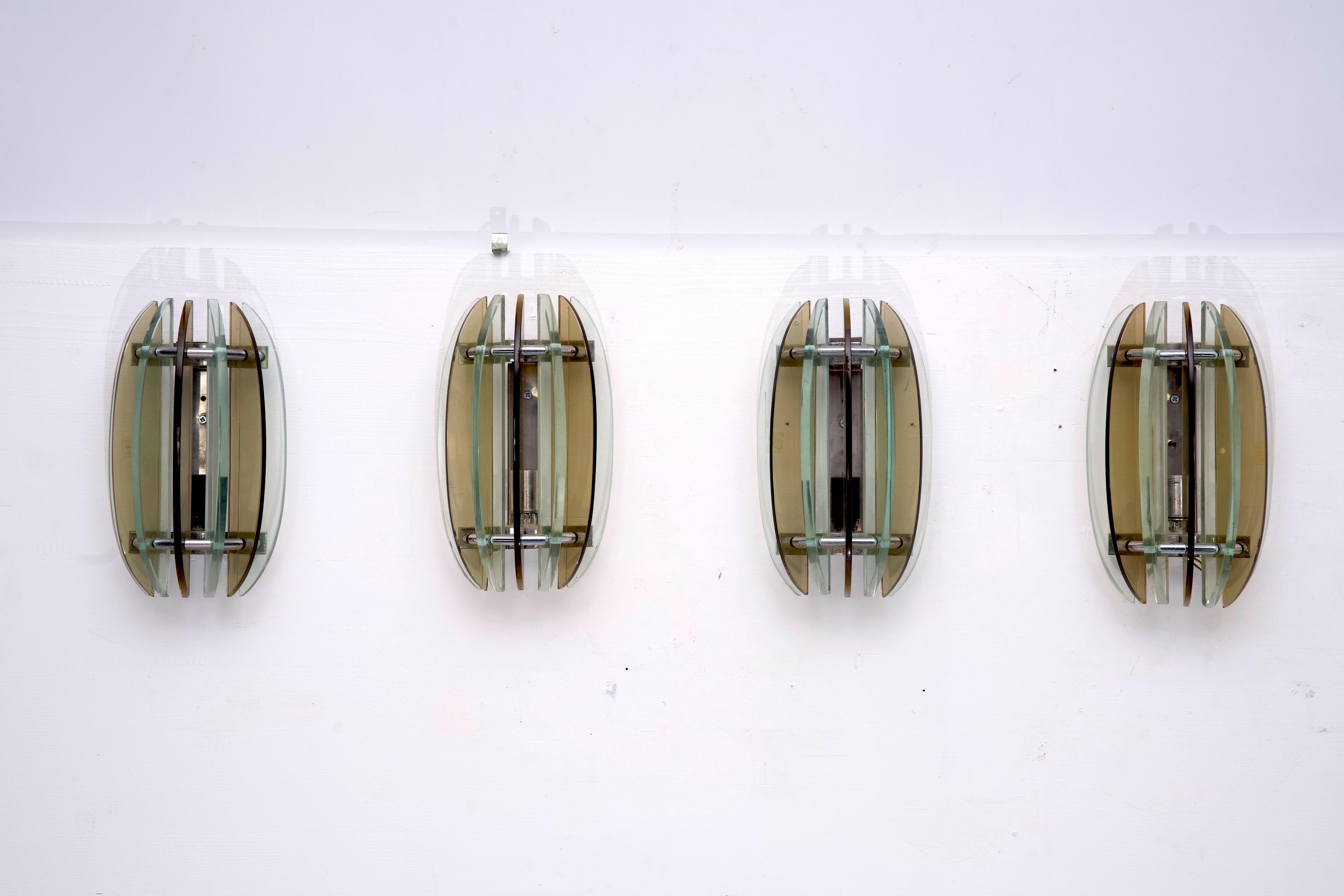 Questo set di quattro appliques, realizzate in vetro spesso e cromo, è stato prodotto da Veca in Italia negli anni '60. Sono in ottime condizioni vintage, con alcuni segni dell'età e dell'uso, ma senza scheggiature o crepe. Funziona completamente