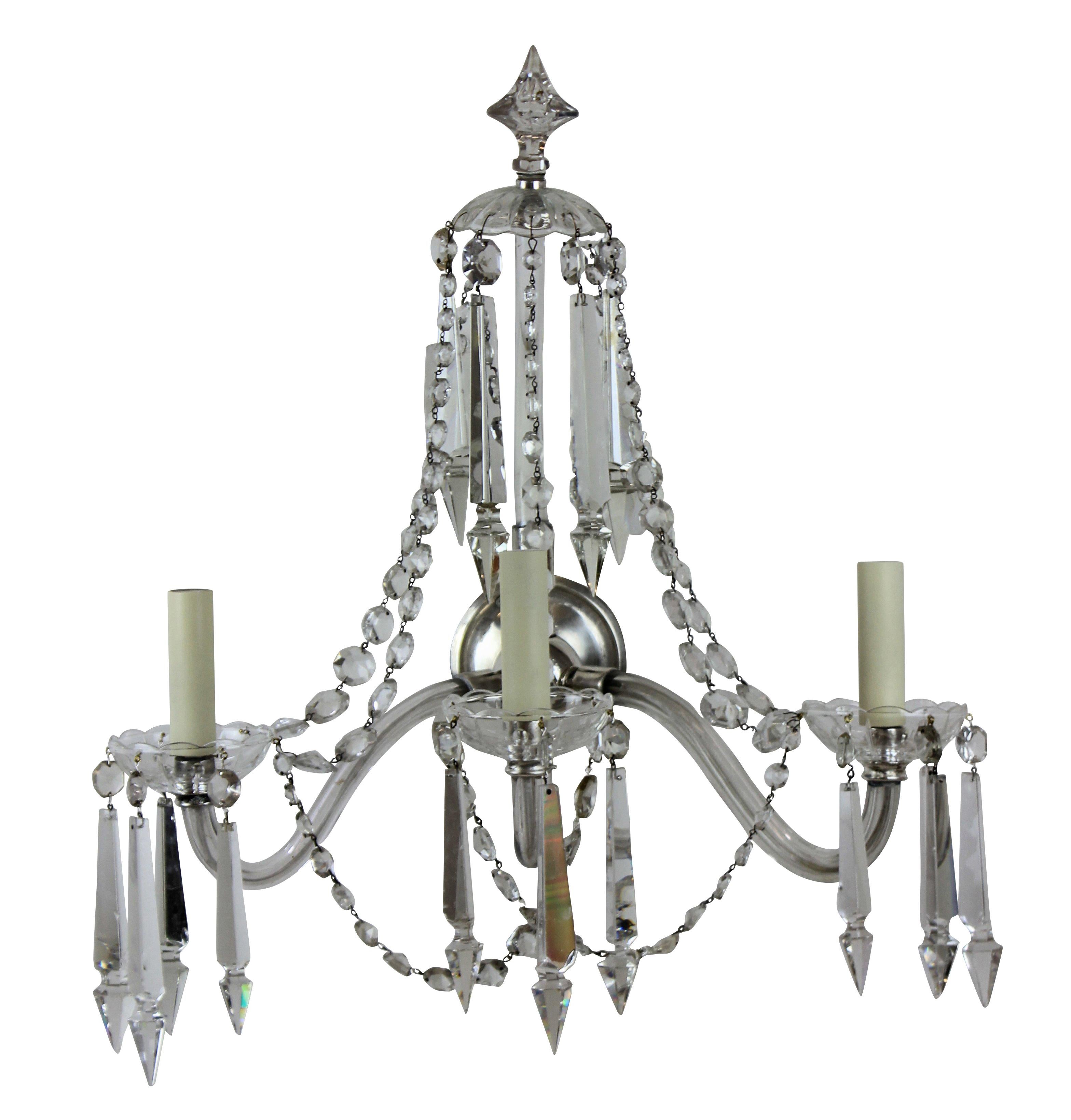 A set of four large English cut-glass wall lights, each with three branches, central spires and swags.
 