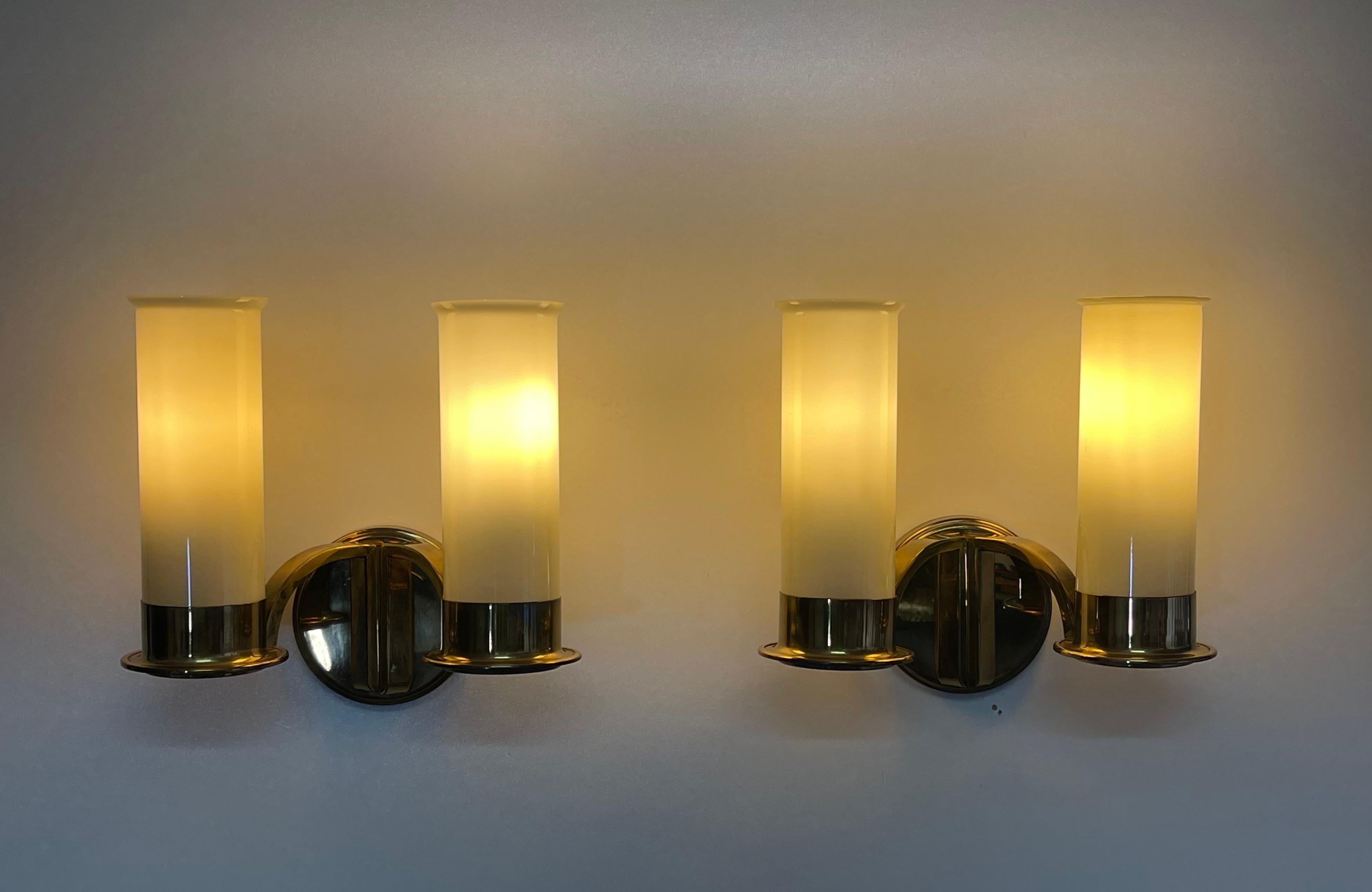 A stunning set of four Art Deco glass and opal brass wall lights, circa 1930s.
Made of polished brass and opal glass tubes.
Socket: each 2 x Edison (e27) for standard screw bulbs.

The condition is excellent.
(A matching chandelier is also