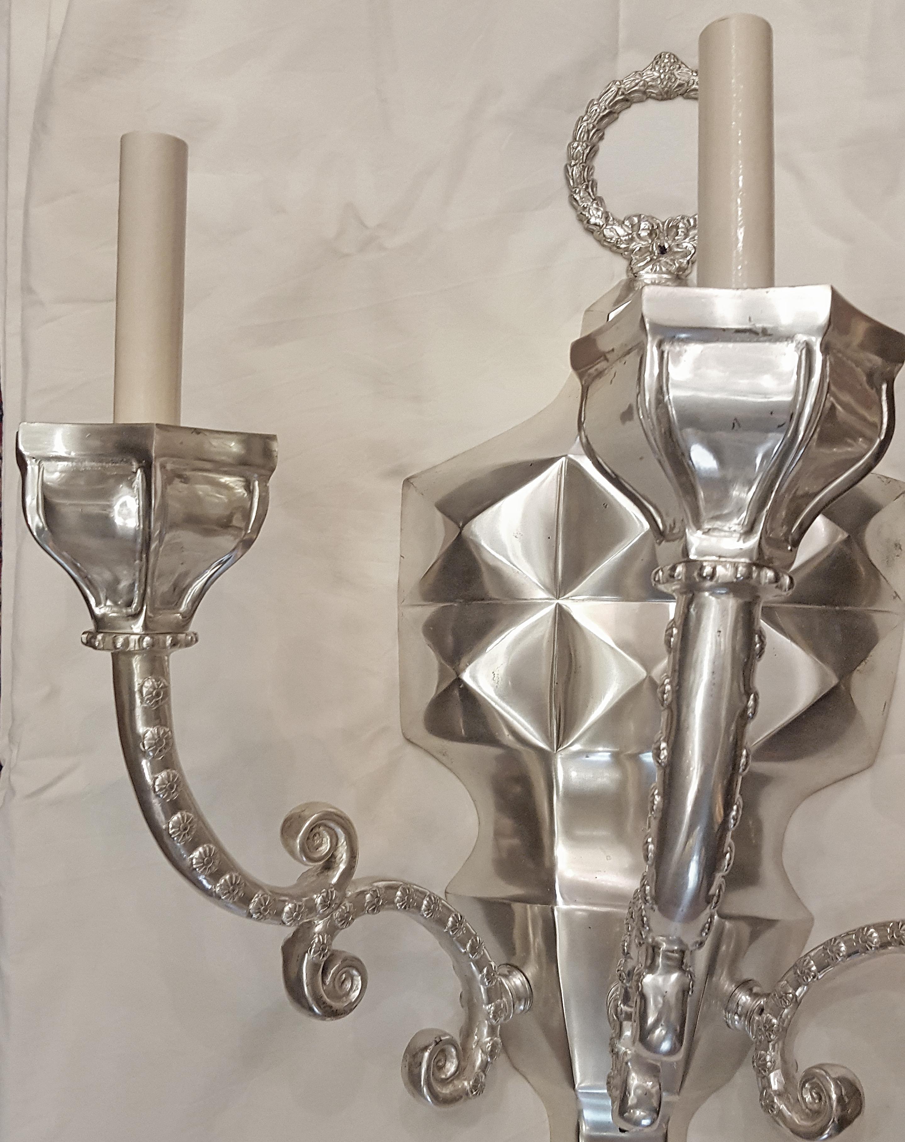 Set of four large neoclassic style, silver-plated, three-arm sconces with tassel motif. Priced and sold in pairs.

Measurements:
Height: 26