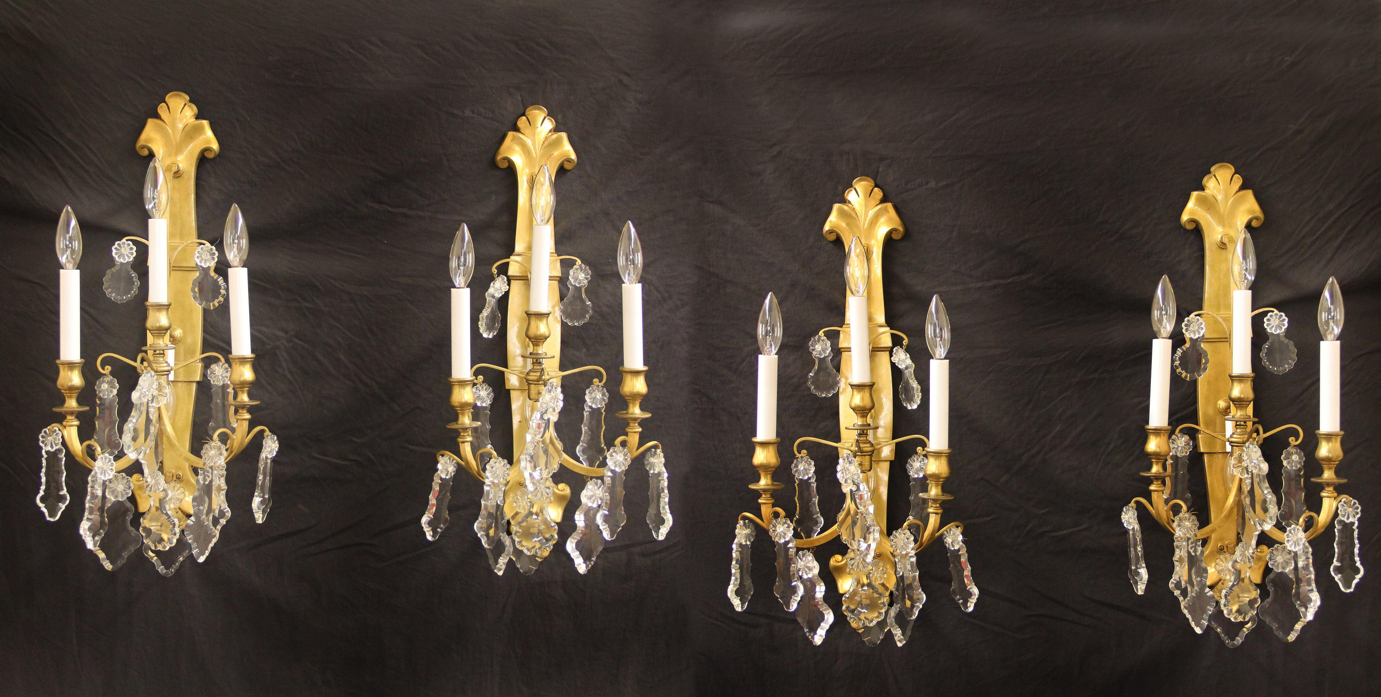 A Set of Four Late 19th / Early 20th Century Gilt Bronze and Crystal Four Light Sconces

Multi-faceted and shaped crystals, three exterior lights and one downward facing interior light.