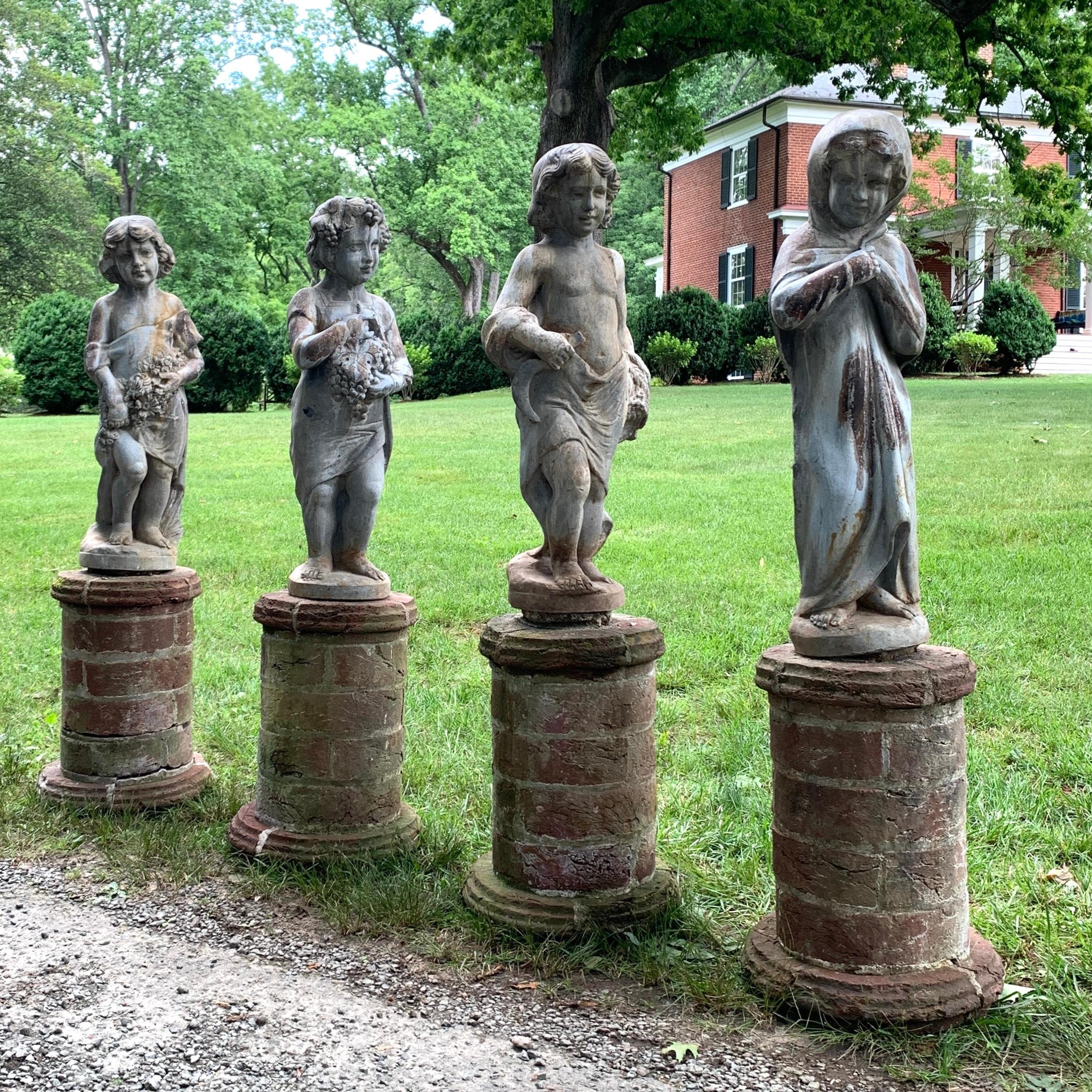 A collection of four early 20th c. English lead garden statues depicting the four seasons in the classical tradition. Each statue stands on a custom-made brick plinth. 

  