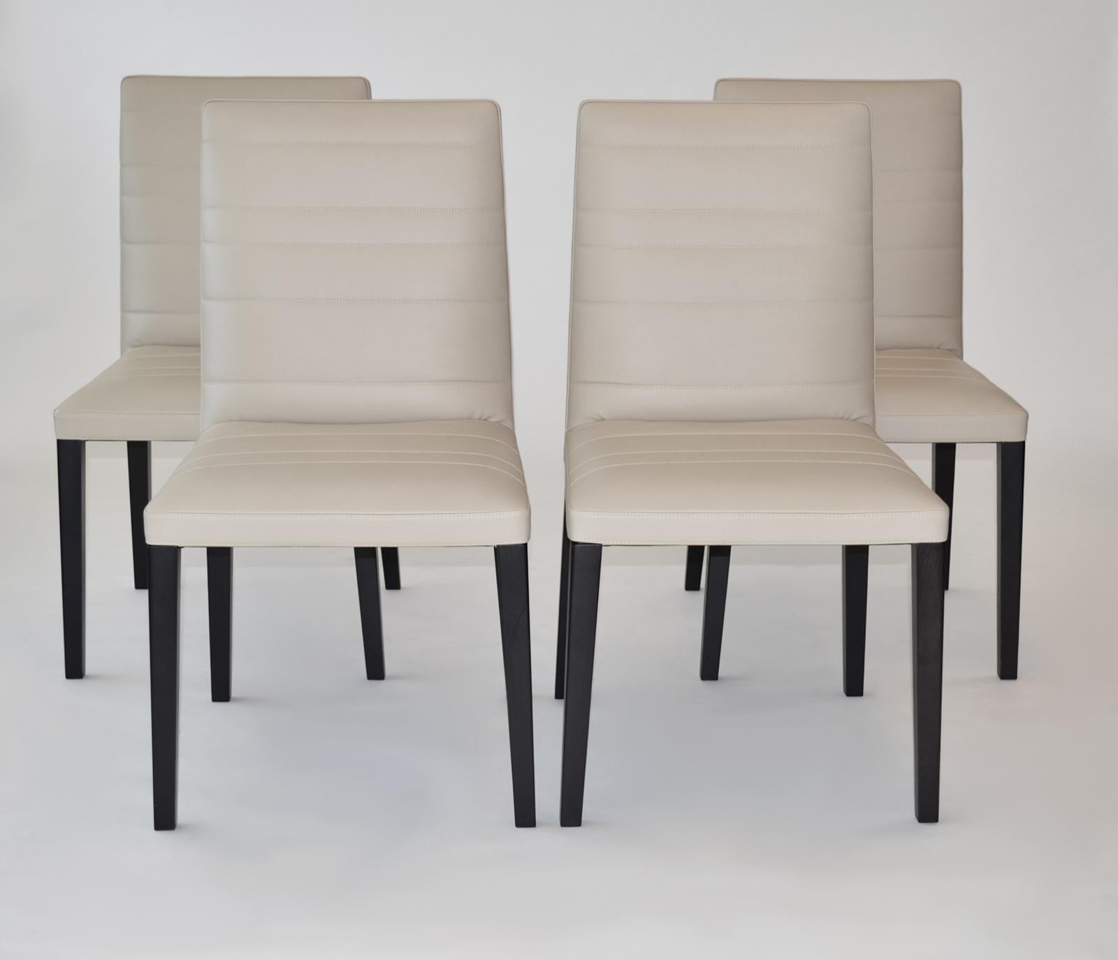 Set of Four Leather and Wood Dining Chairs by Poltrona Frau. 'Louise' 

Color is an off-white to oatmeal. The structure is crafted with solid ash and beech wood with polyurethane foam padding. The springs are made with elastic belts. The legs are