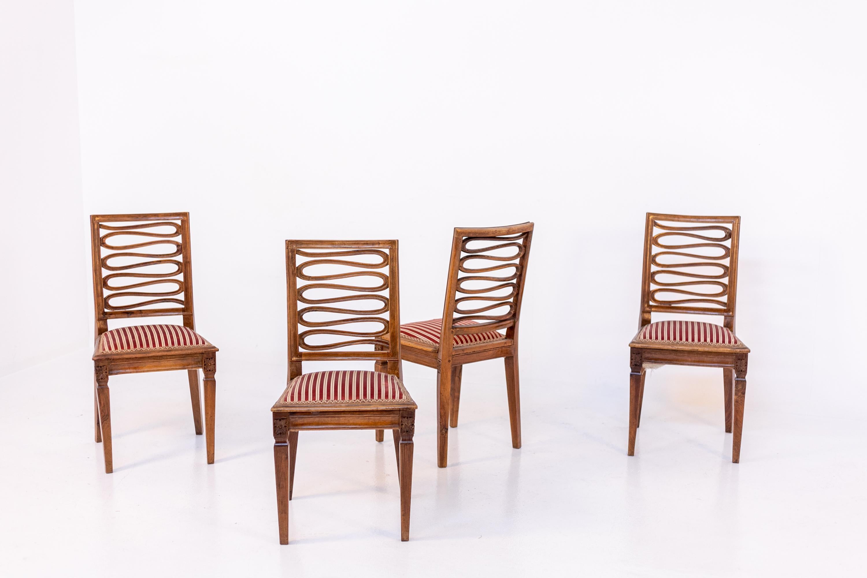 Set of four elegant Louis XVI wooden chairs original to the period in its original condition. The set is elegantly crafted from carved wood. The particularity of the chairs is its egregiously worked back. The back has a snake shape carved into the