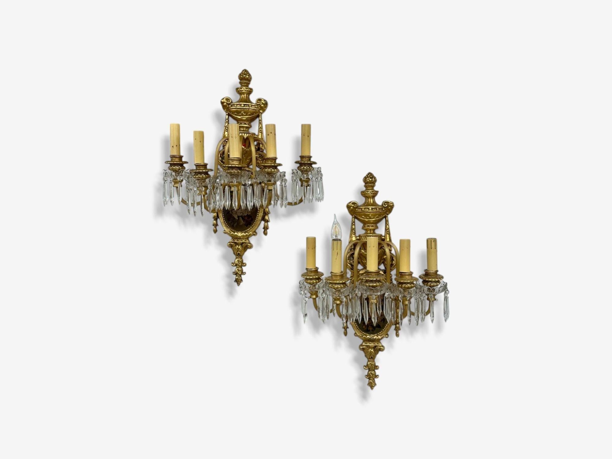French Louis XVI Style, Bronze, Crystal, Rams Head Five Light Sconces. 1920s

Pair of bronze and crystal ram's head and floral plaque decorated sconces. Each Louis XVI Style sconce with ribbon and tassel having a hand painted floral oval scene and