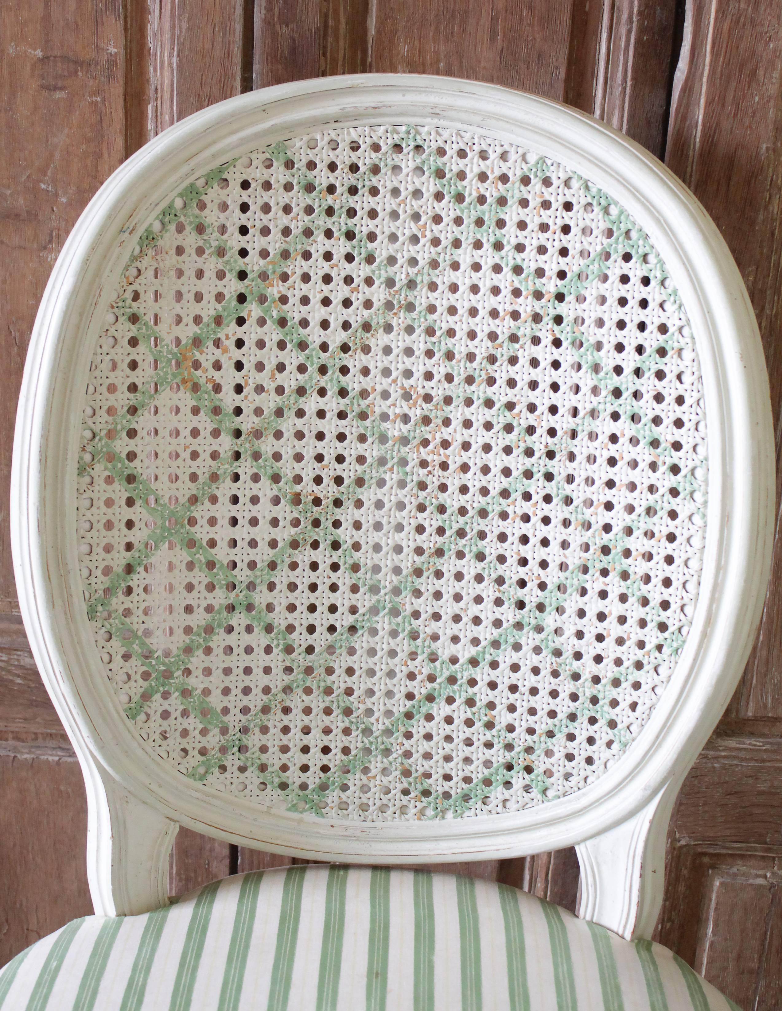 Set of four Louis XVI style French painted cane back dining chairs
Original painted finish, in an off white with a pretty garden green colored painted lattice pattern on the cane backs. Very solid and sturdy, the chairs will just need to be