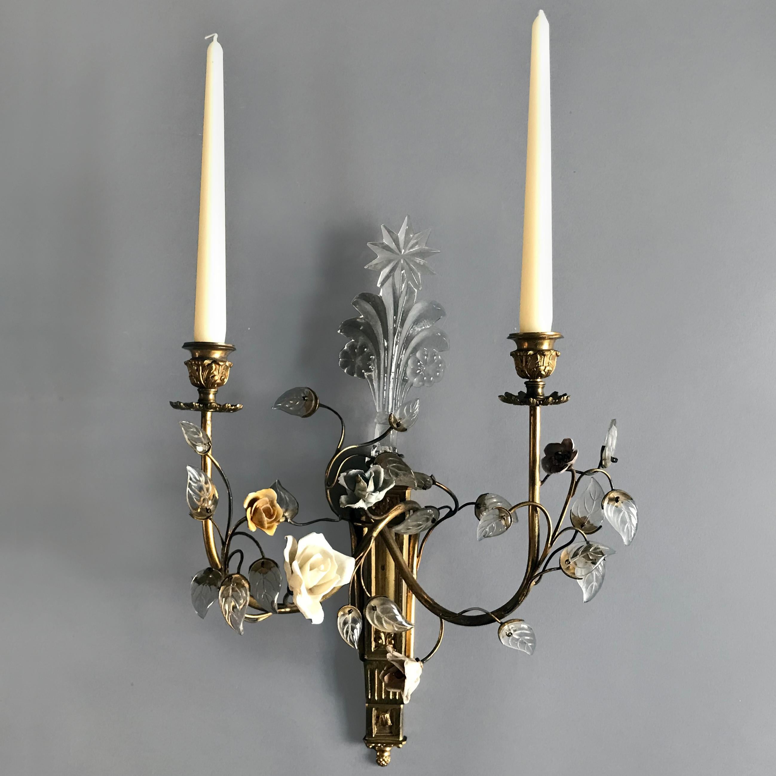 An impressive set of four Louis XVI style gilt bronze and porcelain mounted two and three-branch wall lights. Modelled with porcelain flowers, glass leaves and a flamboyant glass star cresting. Minor nibbles to the porcelain flowers. Measurements