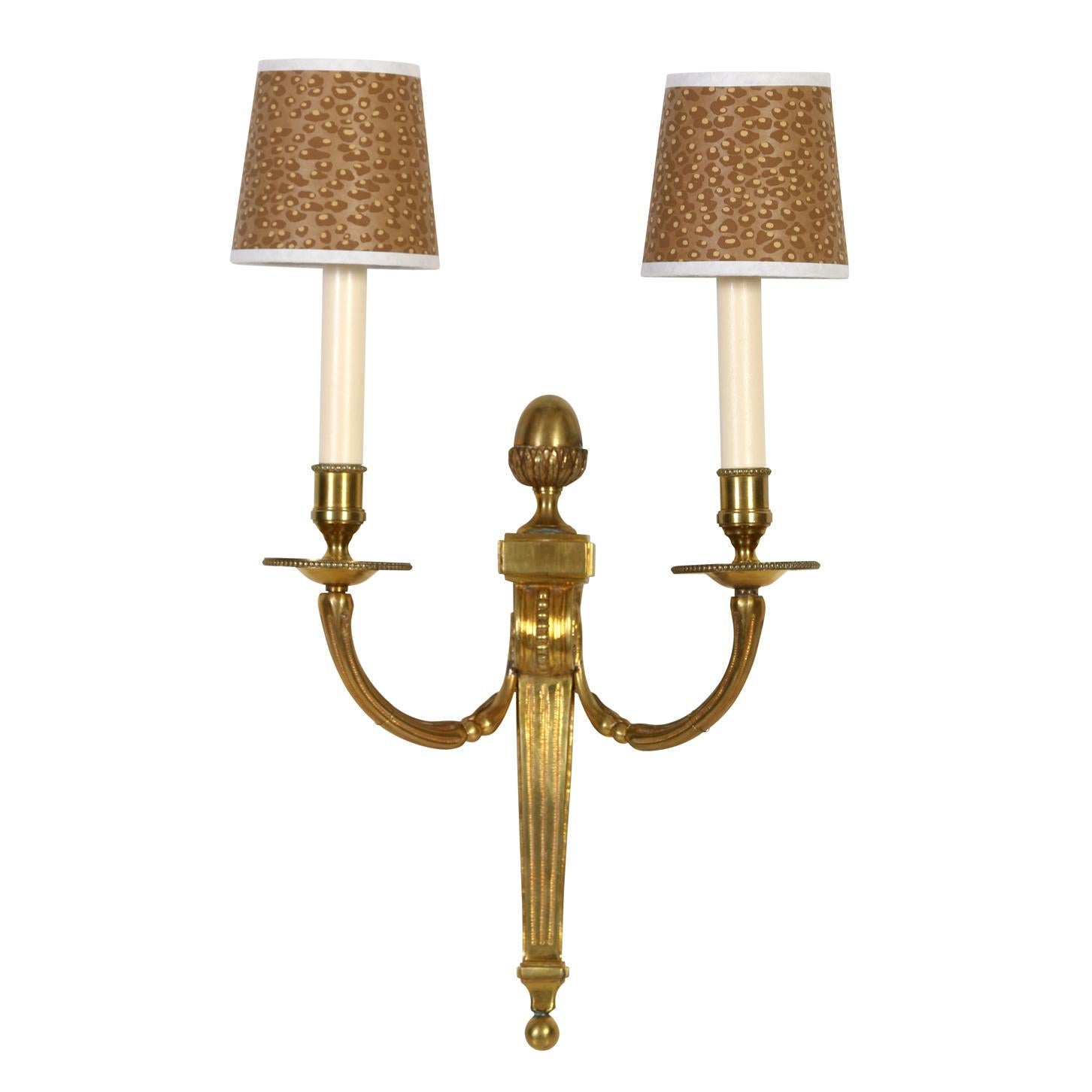 A set of four Louis XVI style gilt bronze, double arm sconces with tapered and reeded center stem and reeded curved arms. Bead detail completes the neoclassical look.  
