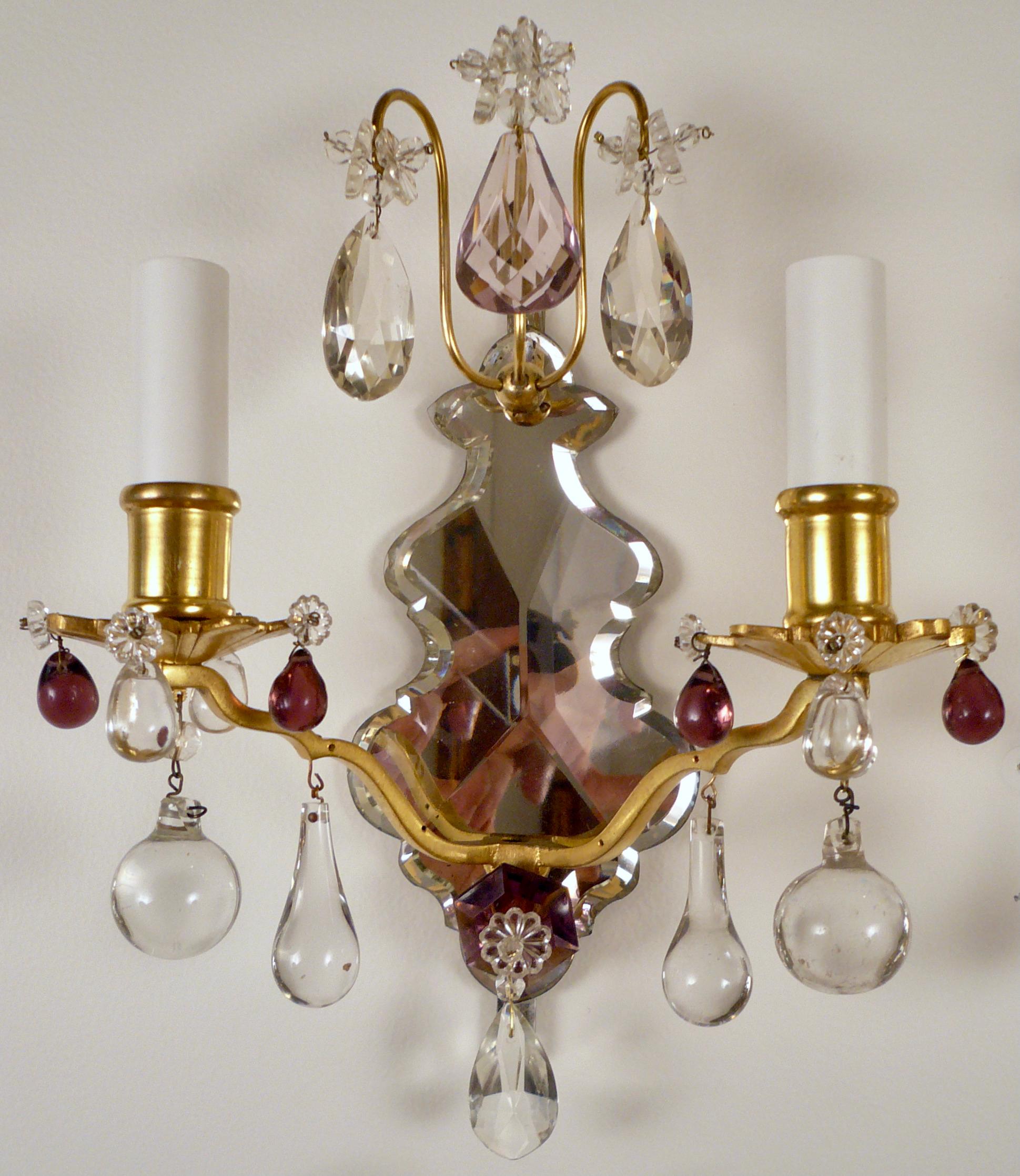 This set of four sconces, having mirrored pendalogue backplates issuing gilt bronze arms and bobesches
feature pale amethyst and clear cut crystal drops.