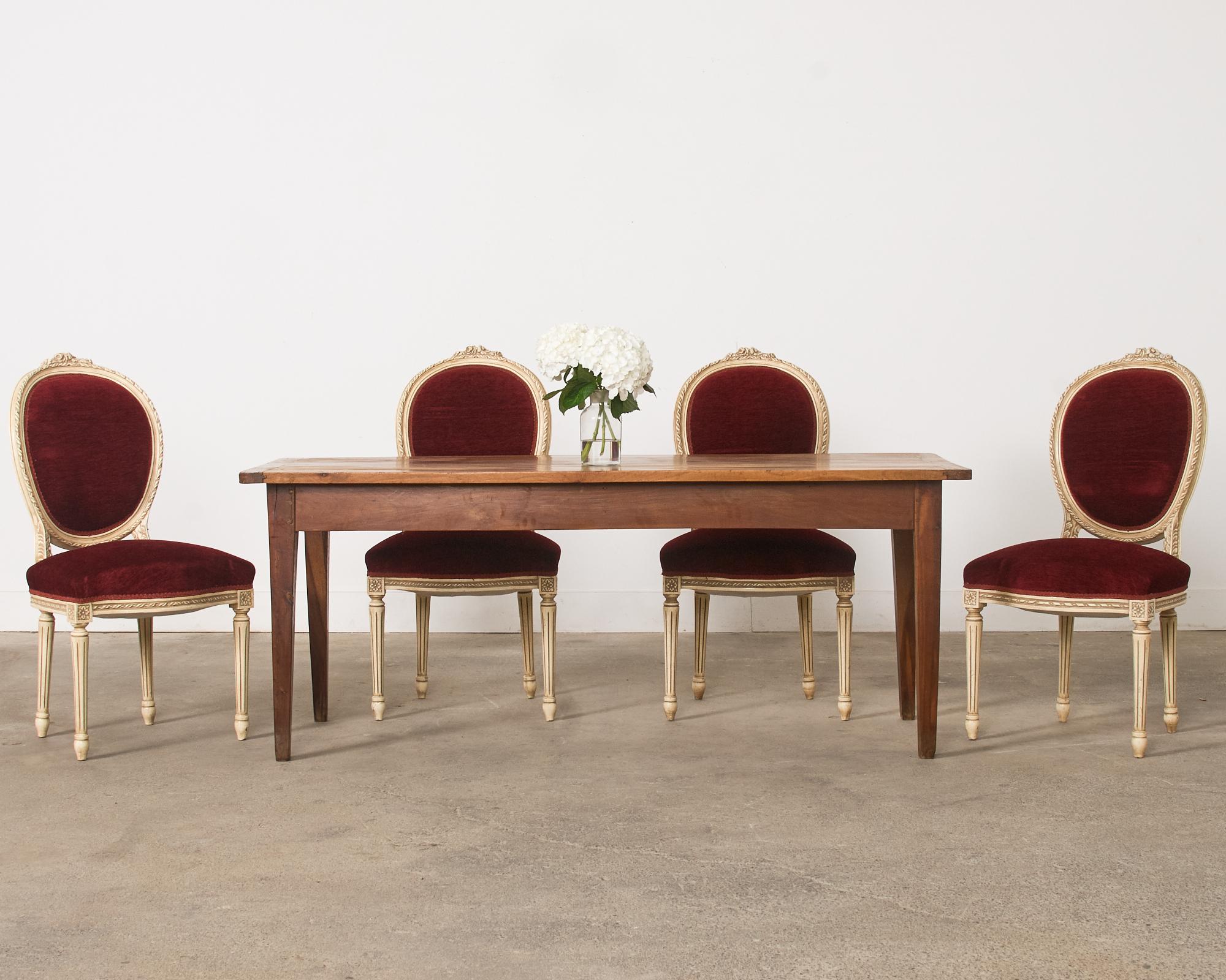 Superbe ensemble de quatre chaises de salle à manger en laque peinte, réalisées dans le grand style Louis XVI français. Les chaises sont dotées d'un cadre magnifiquement sculpté, d'un camée ovale ou d'un dossier en forme de ballon dont le dessus est