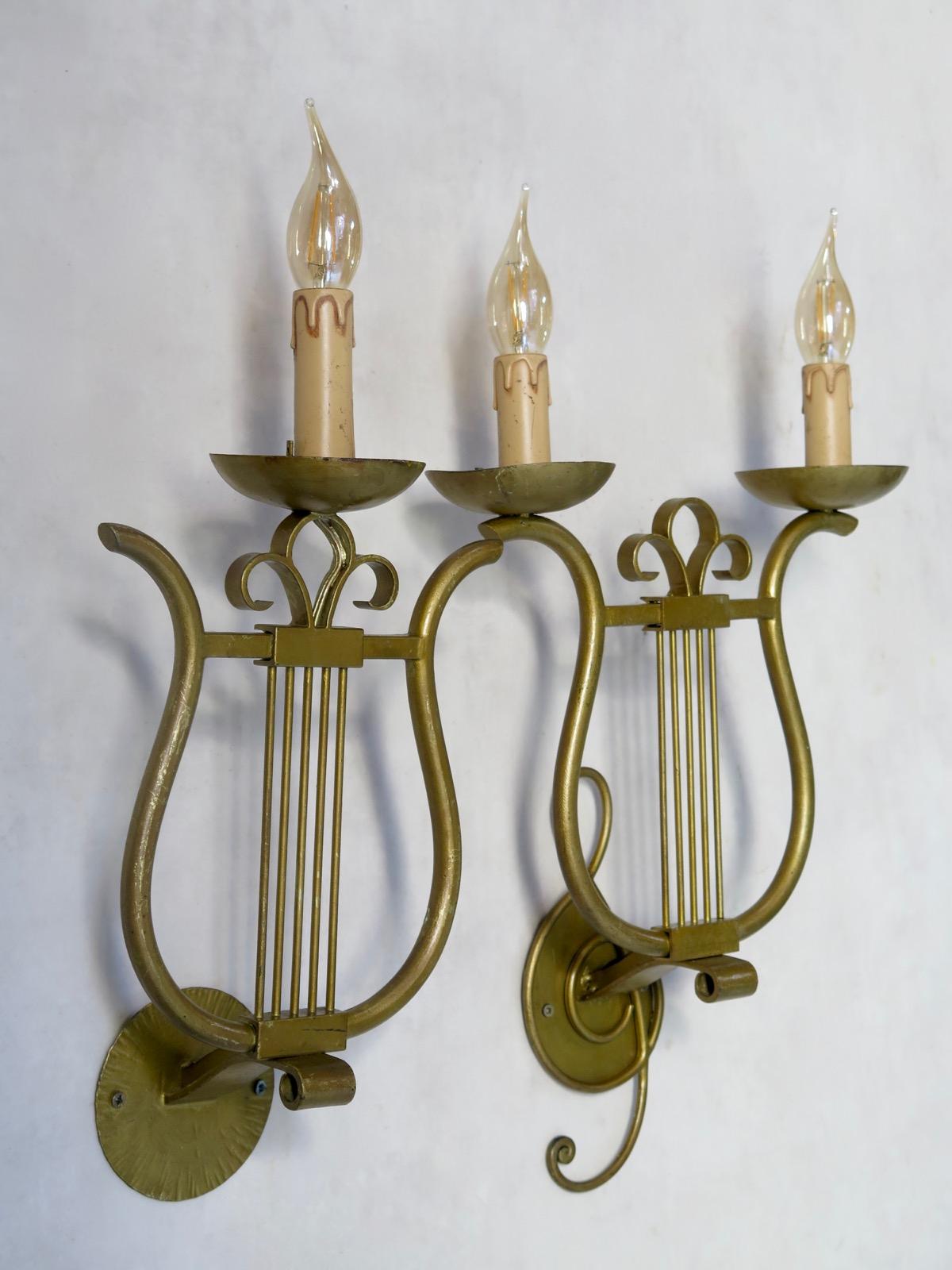 Set of four gilt iron wall lights shaped like lyres. There are two larger ones, with two lights each, and a treble clef. And two smaller, single light ones.

Dimensions provided below are for the larger sconces. The smaller ones